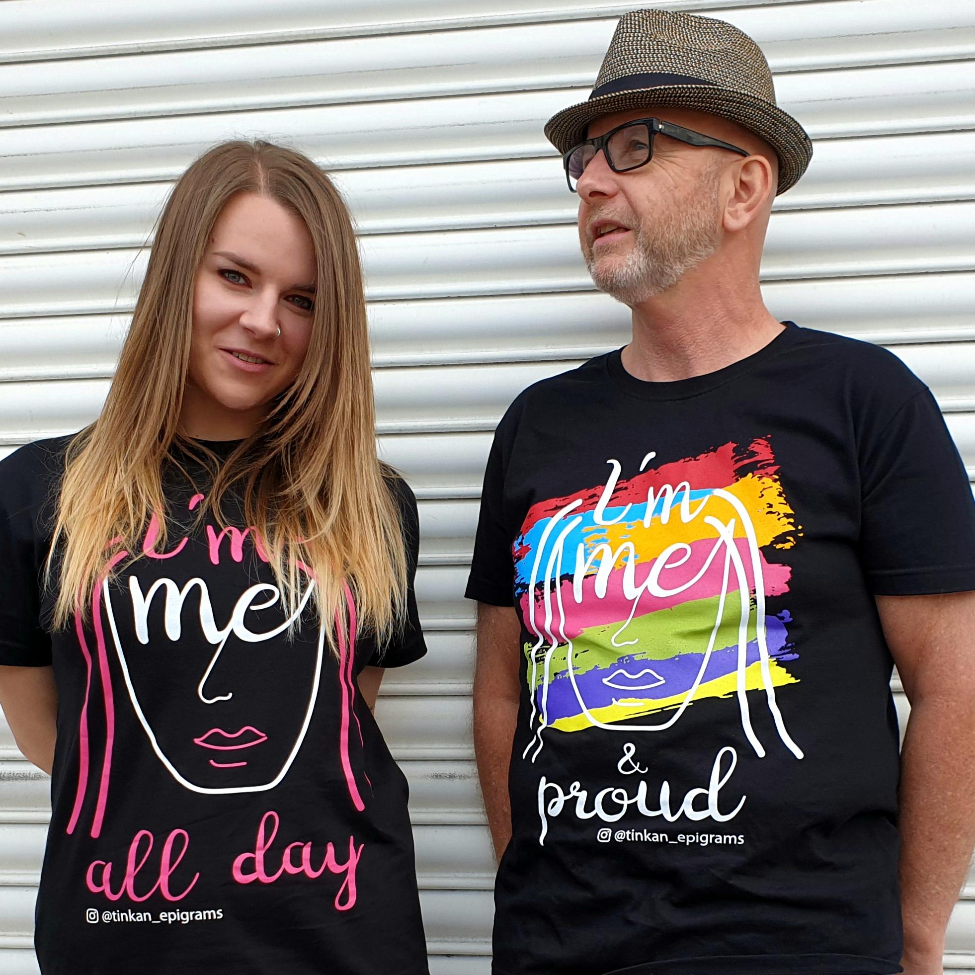Adult female and male wearing black t-shirt with white handdrawn face and rainbow painted stripes with the words I'm Me & Proud printed. Designed by thetinkan. VIEW PRODUCT >>