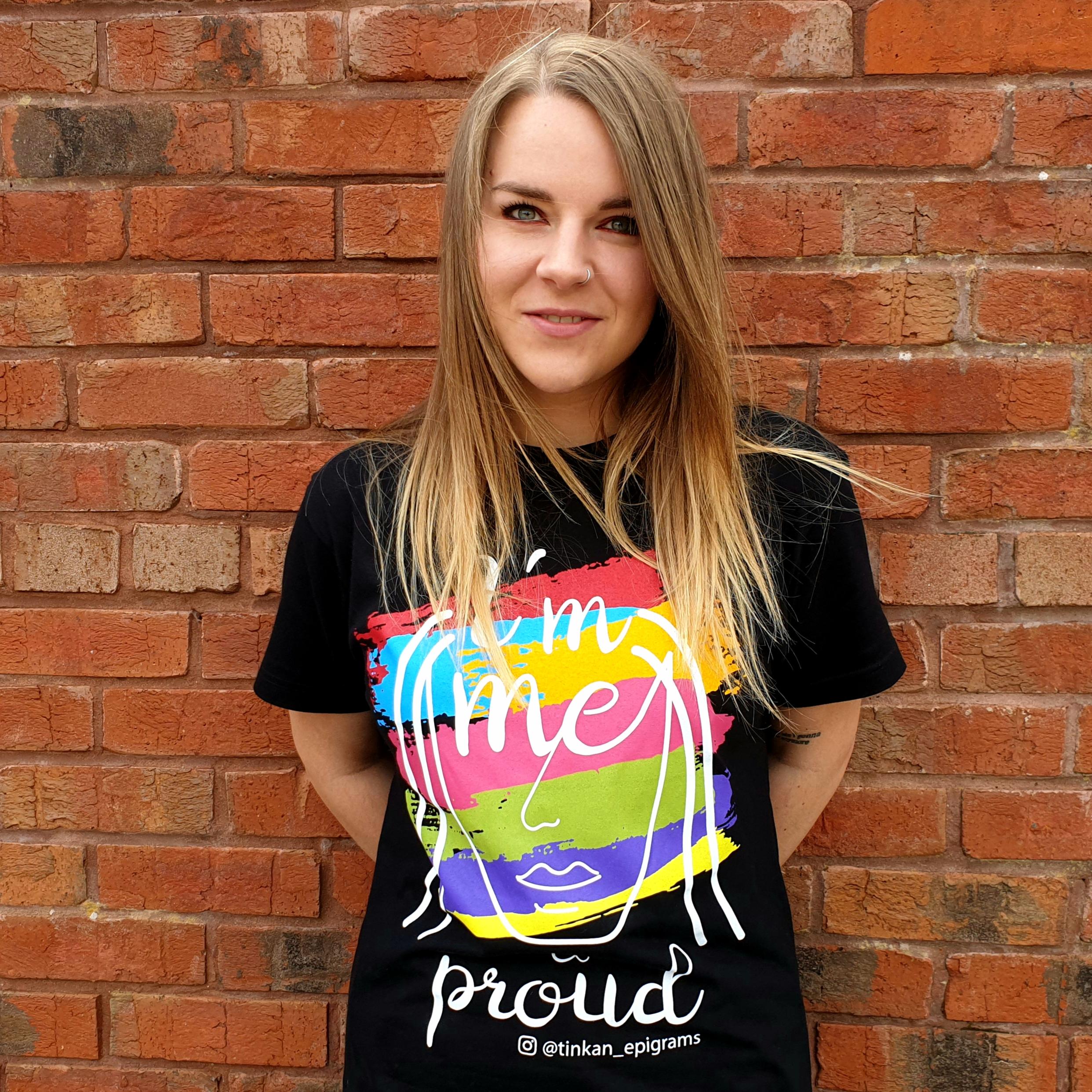 Adult female wearing black t-shirt with white handdrawn face and rainbow painted stripes with the words I'm Me & Proud printed. Designed by thetinkan. VIEW PRODUCT >>