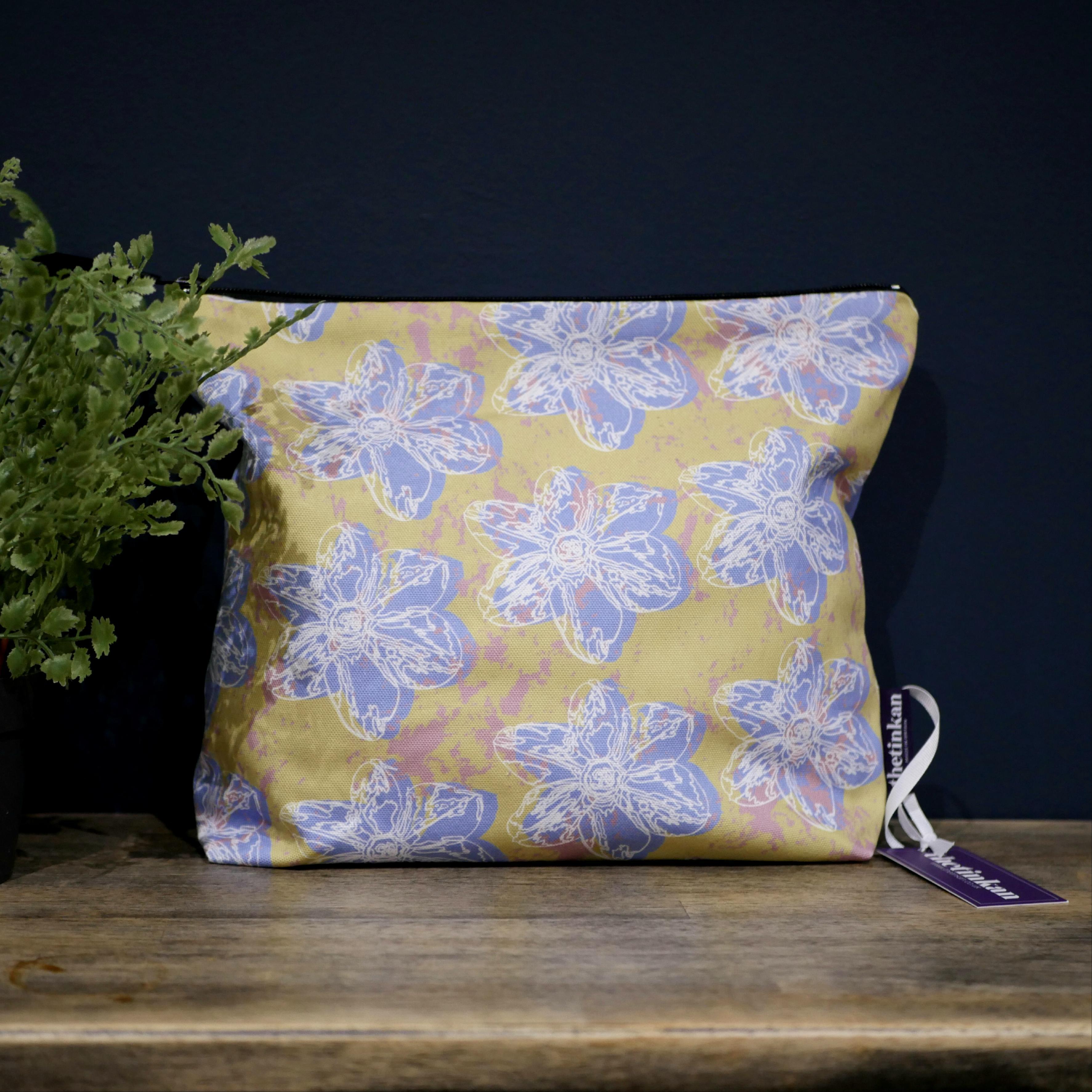 Pale blue flower with a matching coloured reverse, set on an olive green background with a salmon pink colour splash. Designed by thetinkan, the flower splash travel beauty washbag featuring the white traced outline of a?narcissus flower is made from panama cotton with black waterproof lining and matching black sturdy zip. Generously sized for all your travel or home needs.? VIEW PRODUCT >>