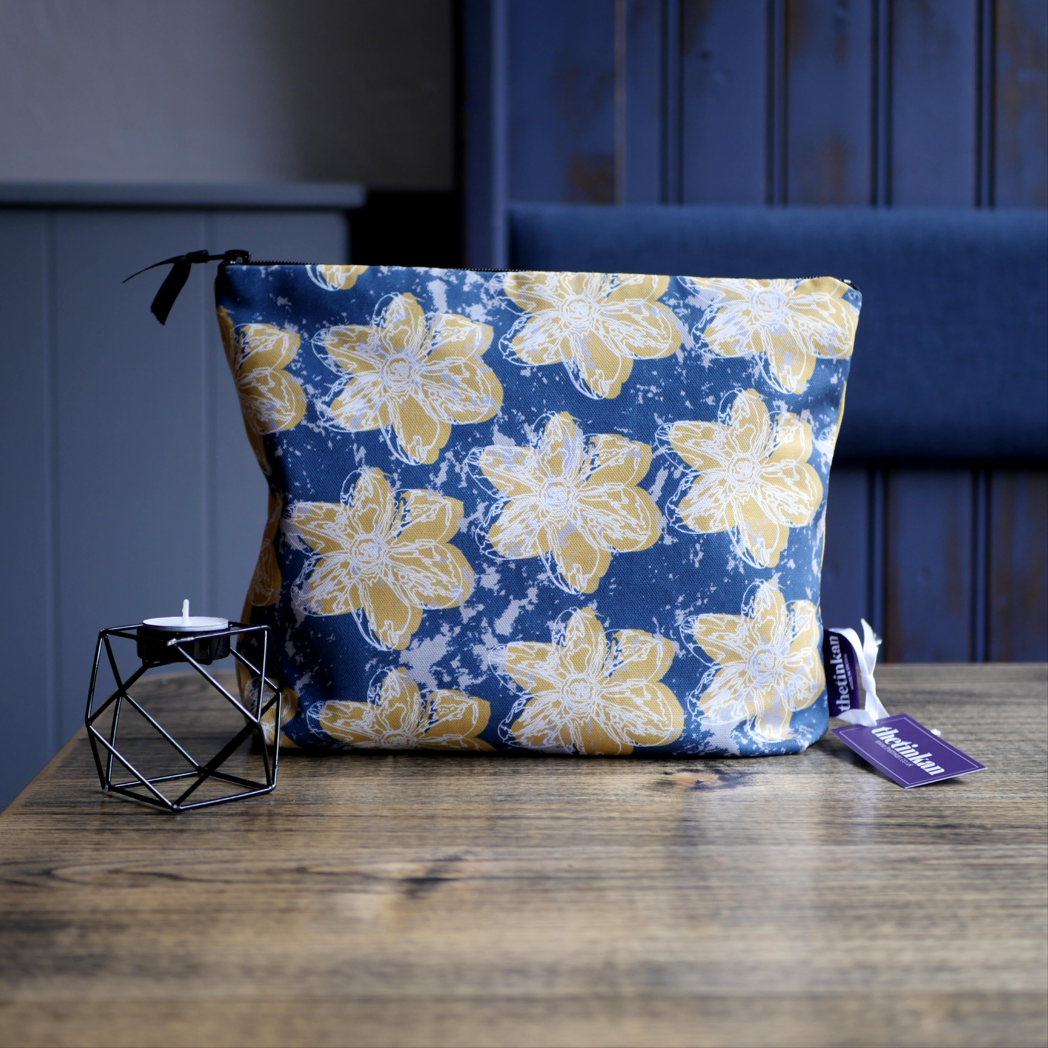 Mustard yellow flower with a matching coloured reverse, set on an oxford blue background with a light grey colour splash. Designed by thetinkan, the flower splash travel beauty washbag featuring the white traced outline of a narcissus flower is made from panama cotton with black waterproof lining and matching black sturdy zip. Generously sized for all your travel or home needs.  VIEW PRODUCT >>