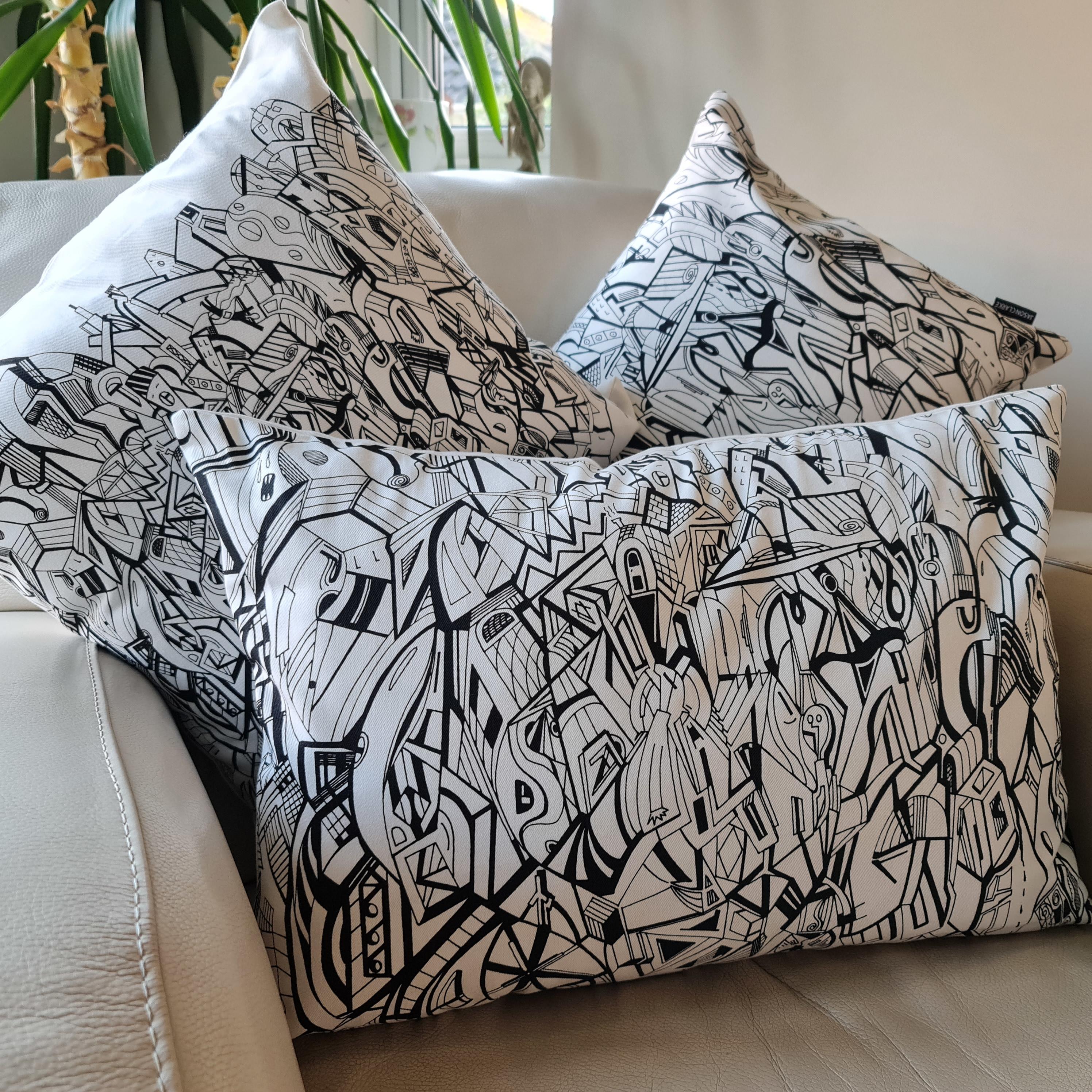 Group photo of cream coloured cotton rectangular cushions with artwork from Jason Clarke printed on the front.