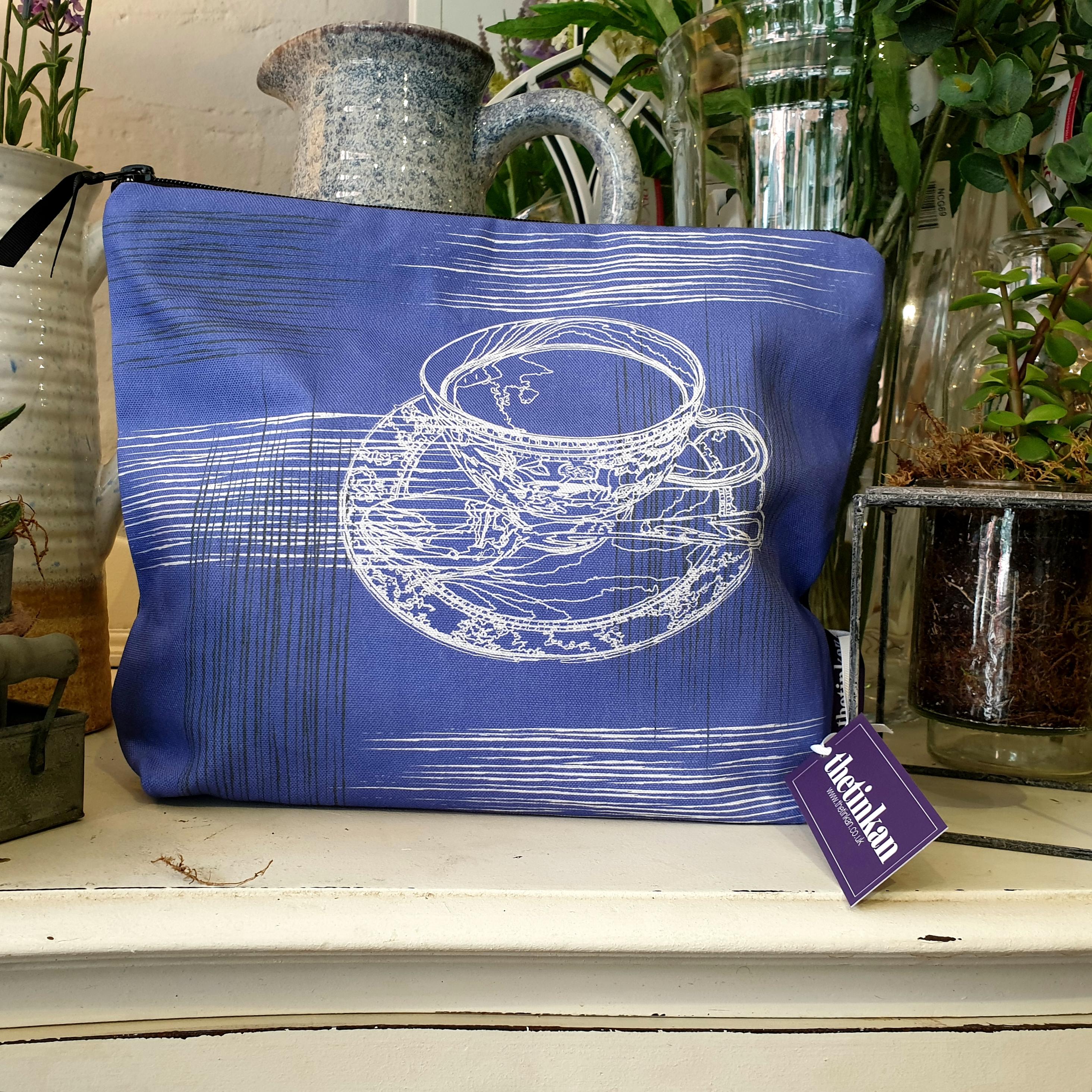 Violet purple with grey coloured reverse, travel beauty washbag featuring the white traced outline of a classic British teacup & saucer. Made from panama cotton with black waterproof lining and matching black sturdy zip. Generously sized for all your travel or home needs. Designed by thetinkan. VIEW PRODUCT >>