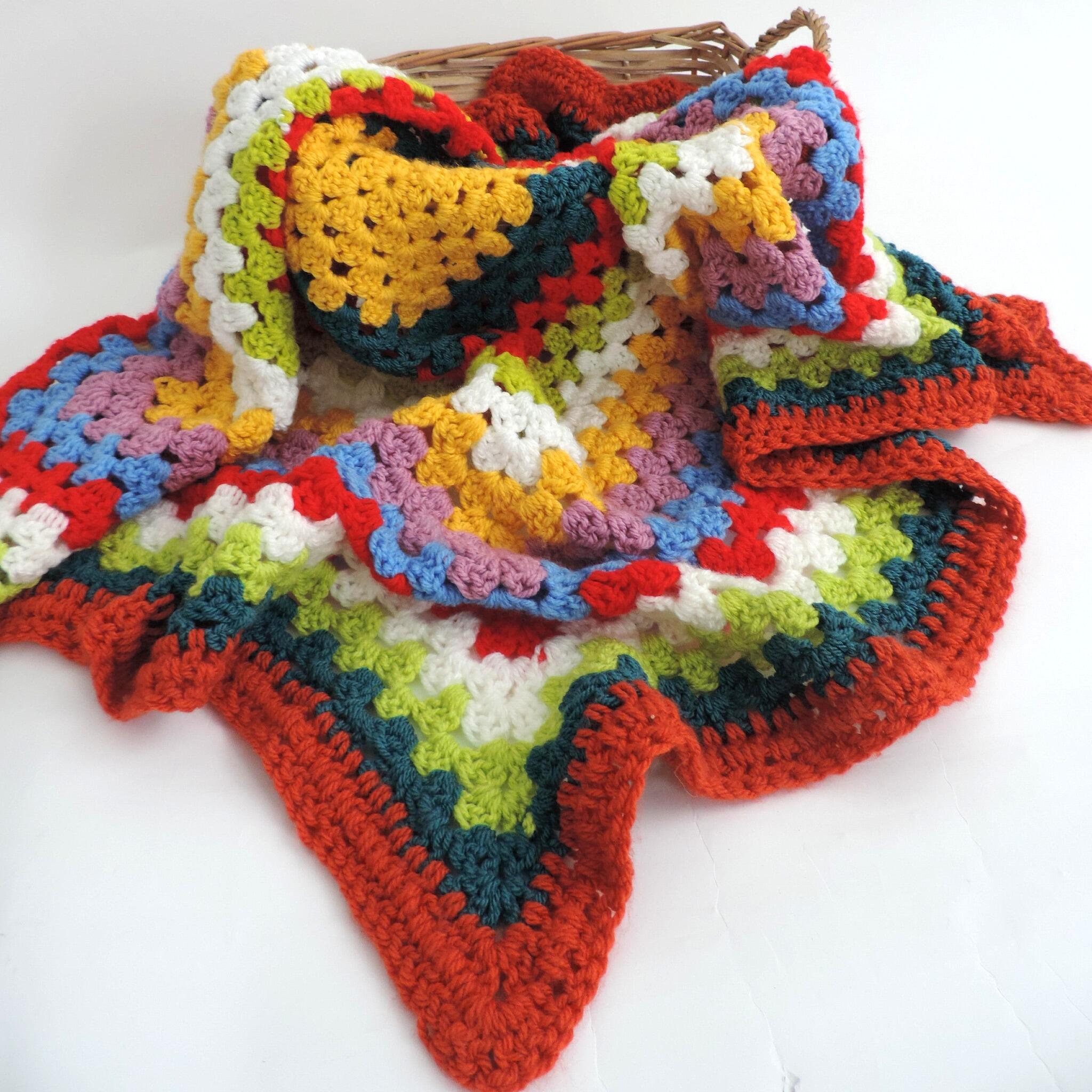 Multi-colourful squared crochet throw blanket in basket