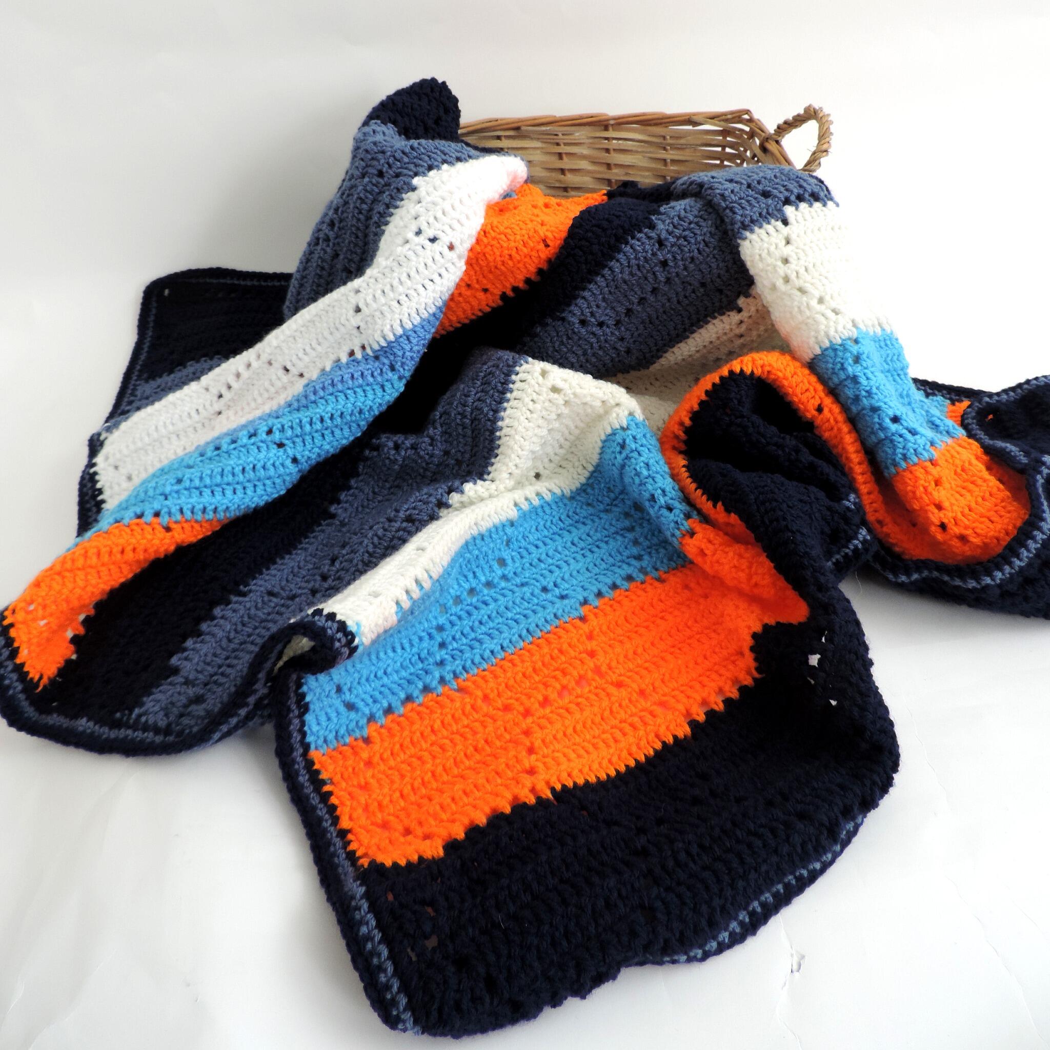 Multi-colourful squared crochet throw blanket blue, grey & orange in a basket