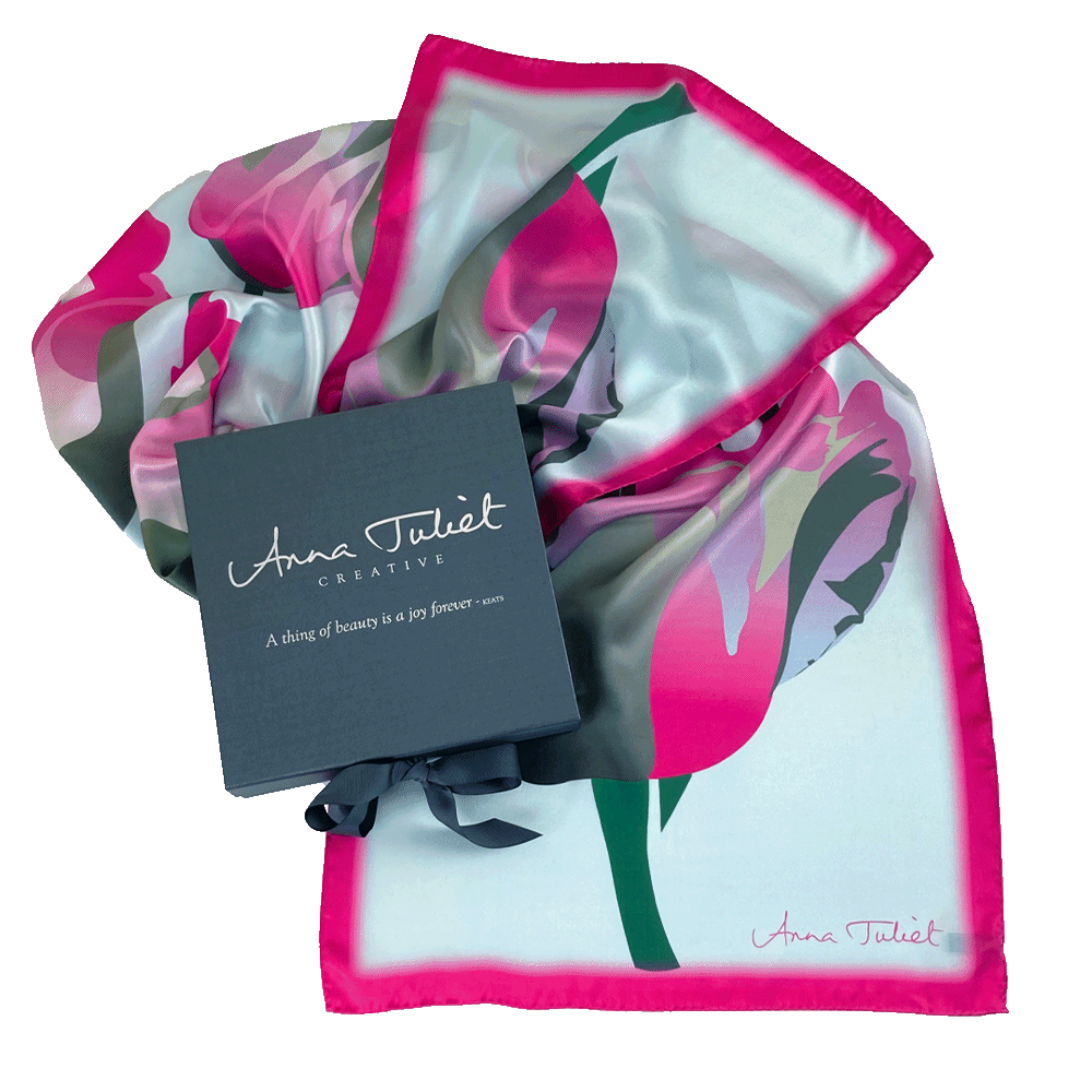 Floral pure silk scarf draped around a branded pewter-coloured gift box. Hot Pink Tulip on Sky Blue limited edition scarf by Anna Juliet Creative.