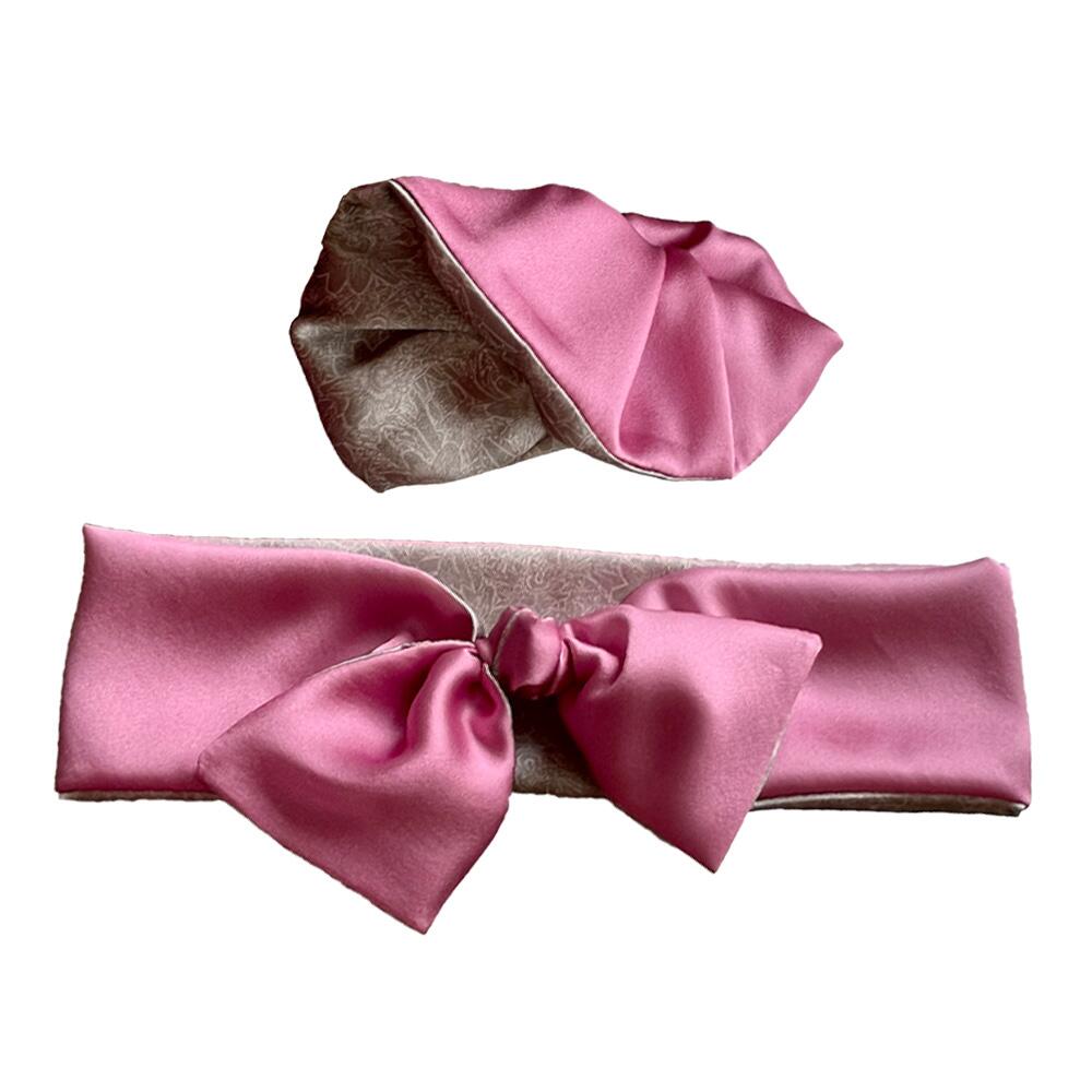 Rose pink coloured adjustable and reversible silk headband and scrunchie luxury gift set made from 95% silk satin and 5% elastane, stretching to fit comfortably. The headband is knotted to form a bow shape and the scrunchie is large (7 cm deep). Both are made with a signature silver-grey patterned silk satin print on the reverse.