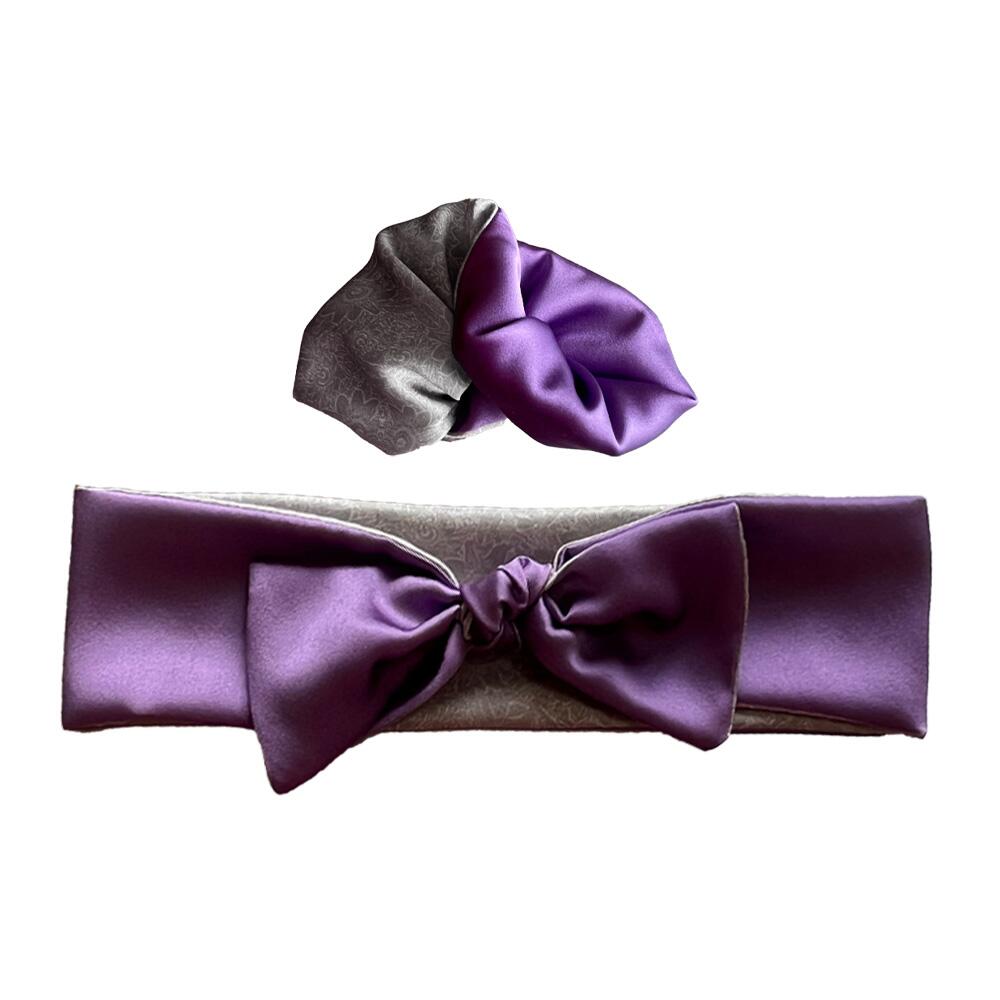 Lilac coloured adjustable and reversible silk headband and scrunchie luxury gift set made from 95% silk satin and 5% elastane, stretching to fit comfortably. The headband is knotted to form a bow shape and the scrunchie is large (7 cm deep). Both are made with a signature silver-grey patterned silk satin print on the reverse.