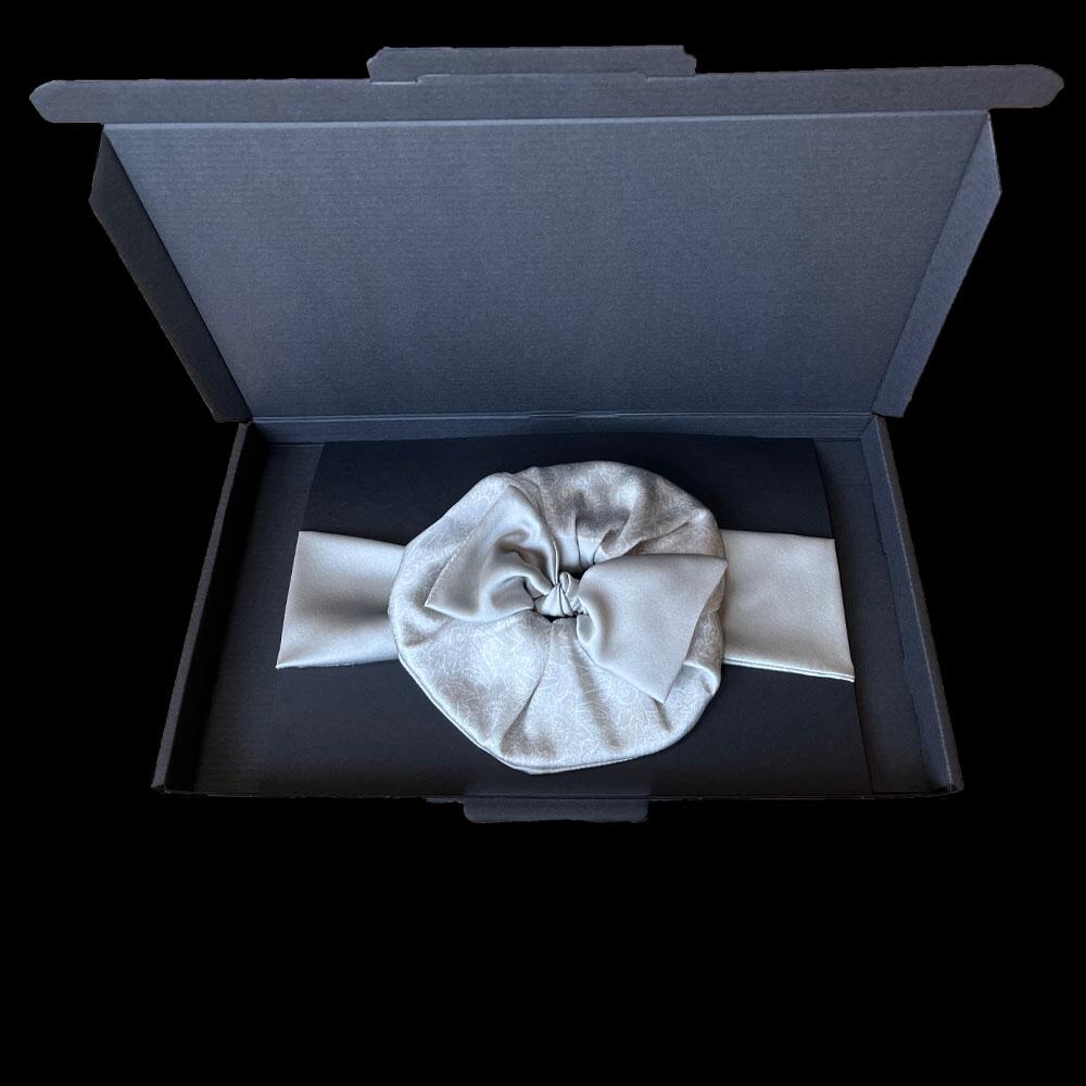 Silver grey silk scrunchie and headband displayed in a black gift box.