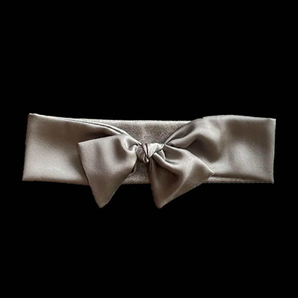 Silver grey coloured adjustable and reversible silk headband made from 95% silk and 5% elastane. The headband is knotted to form a bow shape and made with a signature silver-grey patterned silk satin print lining.
