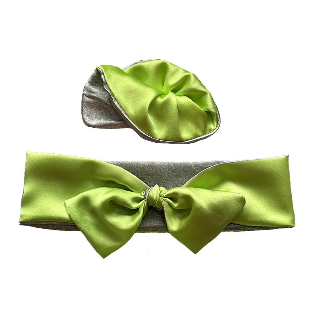 Peridot green coloured adjustable and reversible silk headband and scrunchie luxury gift set made from 95% silk satin and 5% elastane, stretching to fit comfortably. The headband is knotted to form a bow shape and the scrunchie is large (7 cm deep). Both are made with a signature silver-grey patterned silk satin print on the reverse.