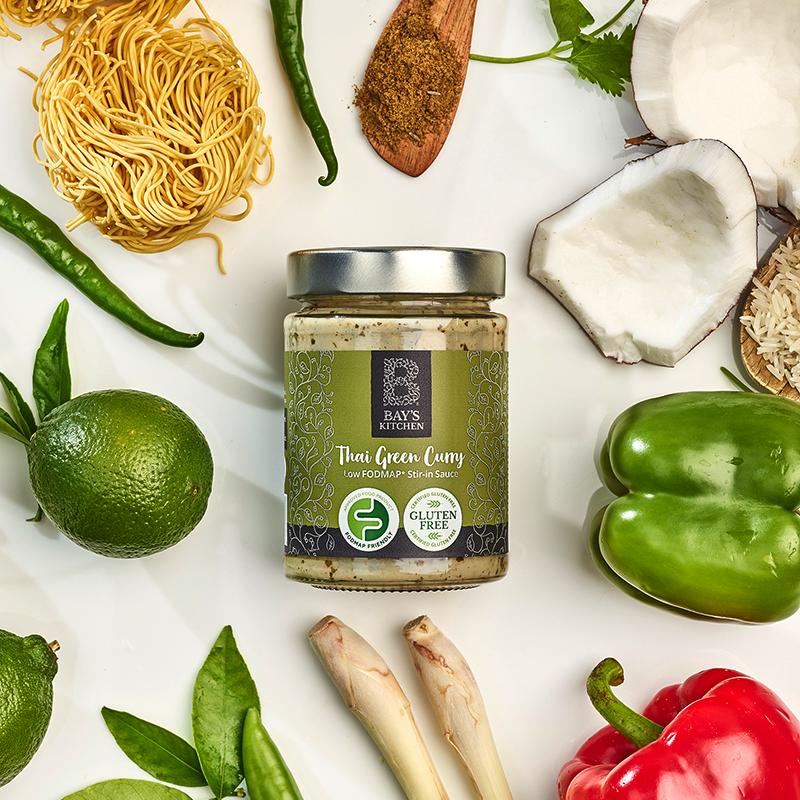 A jar of Bay's Kitchen Thai Green Curry sauce surrounded by its ingredients