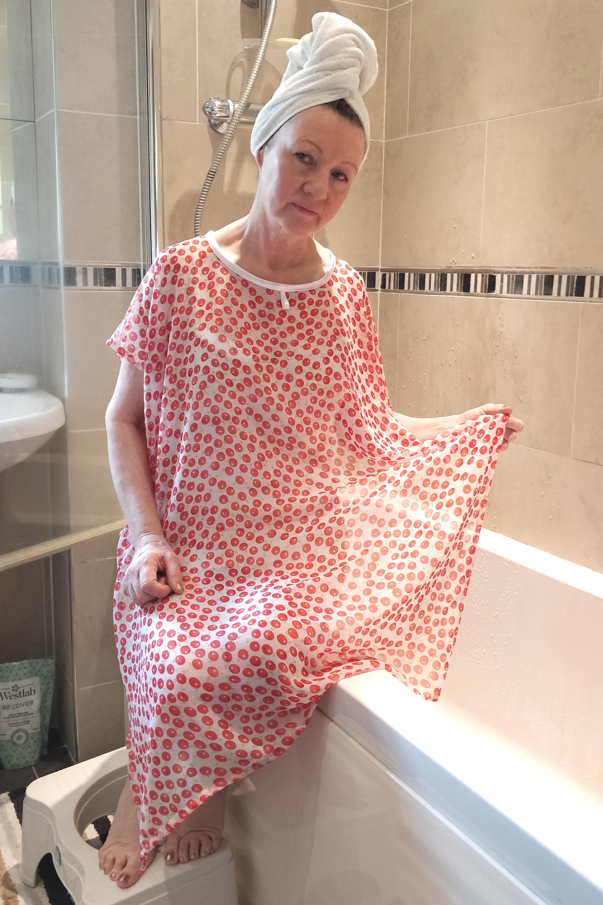 Soft Red NeverNaked(tm) Shower Drapron® to provide modesty, dignity and privacy whilst being helped to shower or bathe. Shower modesty wear. Bathing modesty gown. Lightweight crepe chiffon. Slips over shoulders - No sleeves. Magnetic fastening at back. Like a shower dress