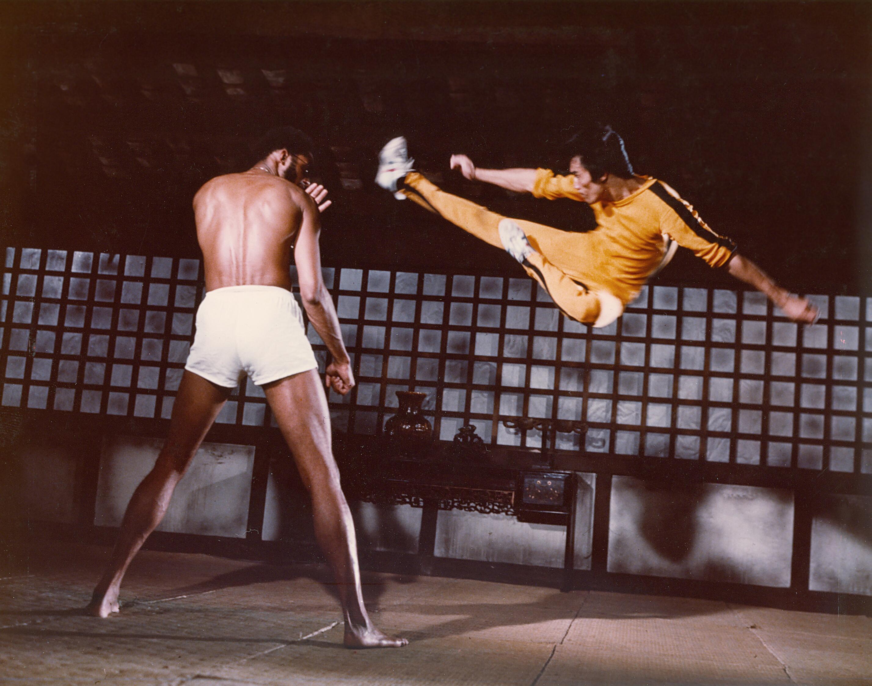 Bruce Lee suspended in air performing a flying kick against his opponent, from the movie Game of Death