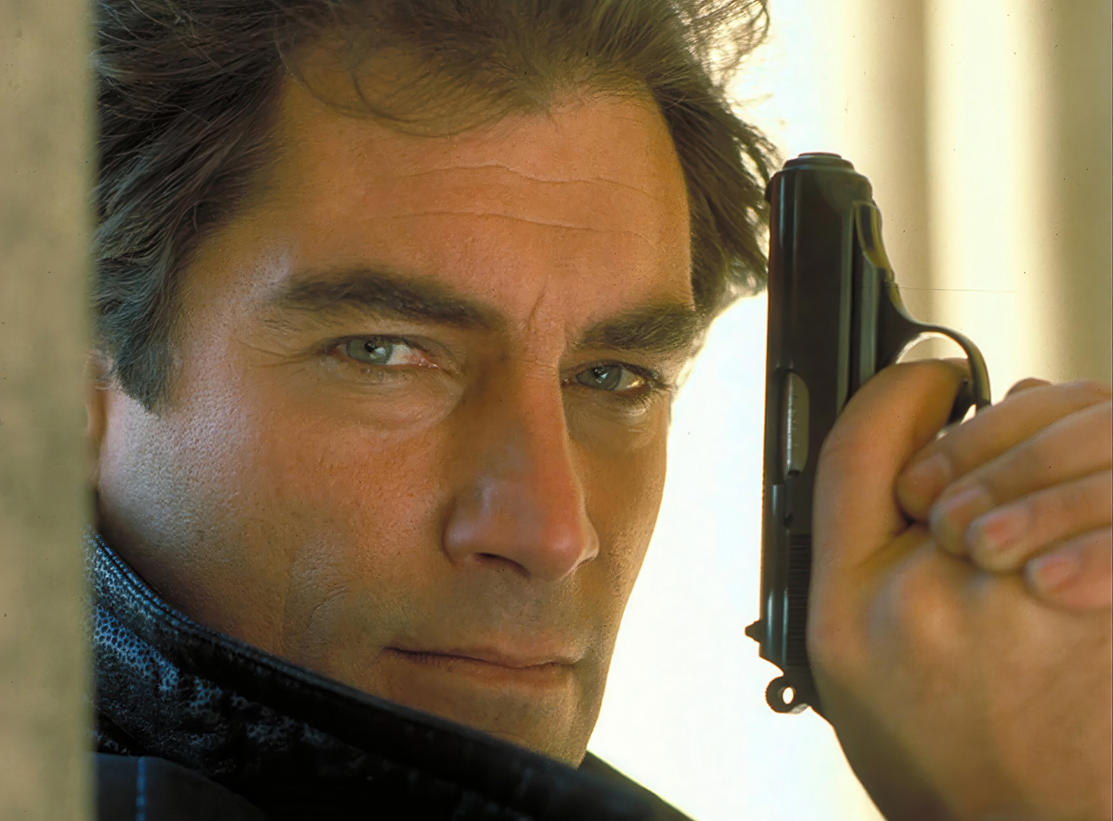 Timothy Dalton posing for a publicity shot with James Bond’s iconic Walther PPK for The Living Daylights (1987).