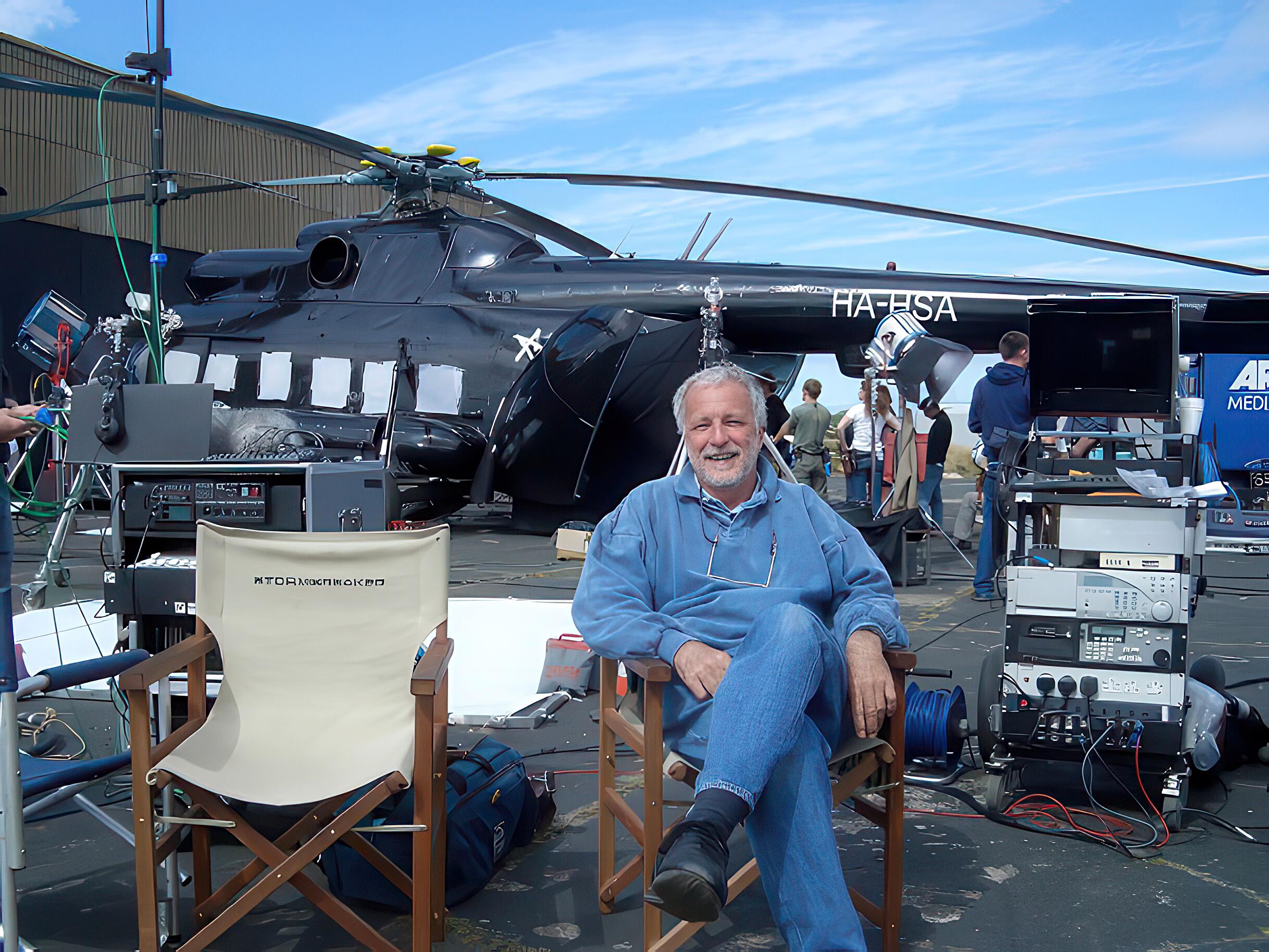 Veteran stunt-pilot and aerial cameraman, Marc Wolff, photographed on set with a helicopter in the background.