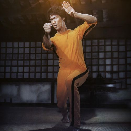 Bruce Lee in fighting pose, wearing his iconic yellow jumpsuit from Game of Death