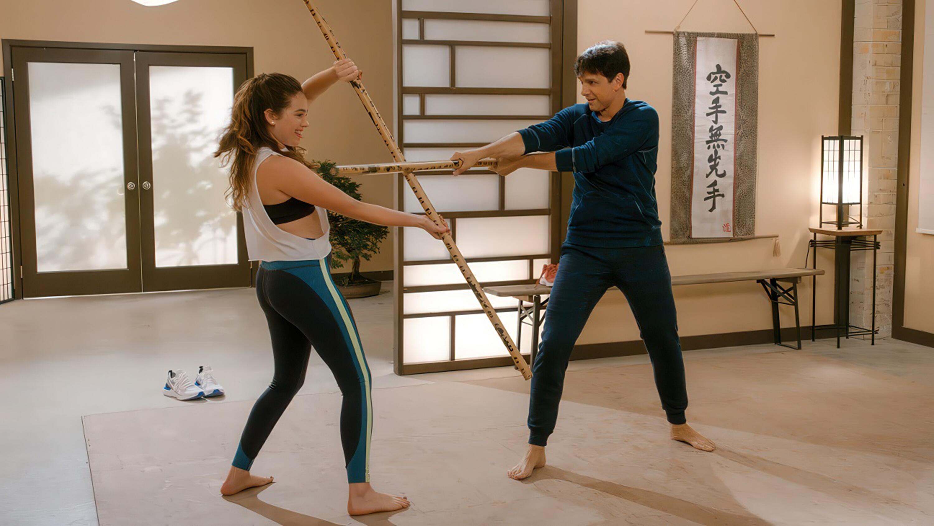 Daniel LaRusso (Ralph Macchio) and Samantha LaRusso (Mary Mouser) practising with the Bo Staff in Cobra Kai