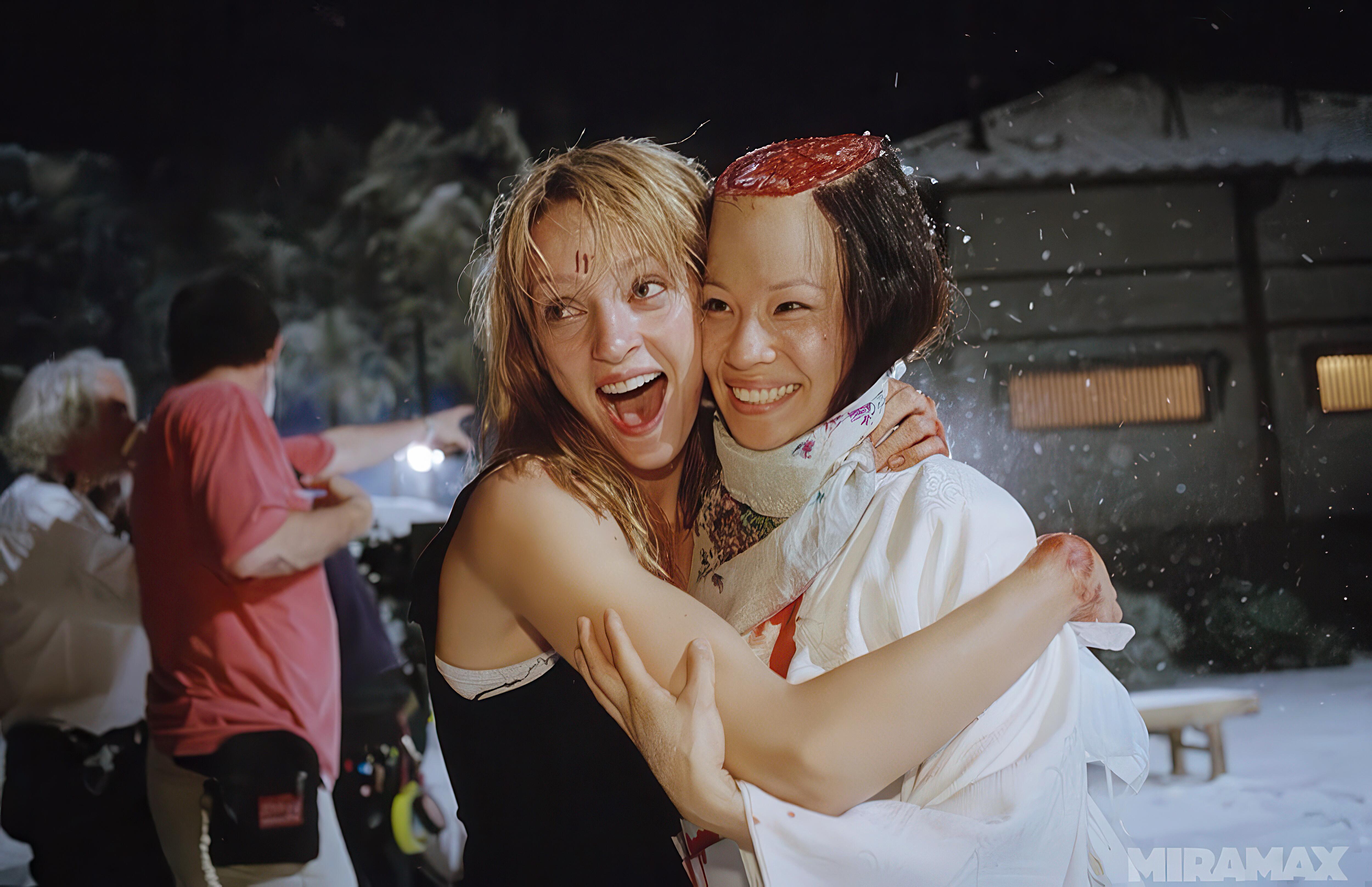 Actresses Uma Thurman and Lucy Liu enjoying a moment of fun together at the close of filming for climactic fight scene between  The Bride and O-Ren Ishii. Lucy Liu is wearing a production-made prosthetic skull cap to made it appear that the top of her head has been chopped, giving the image a darkly comedic vibe.