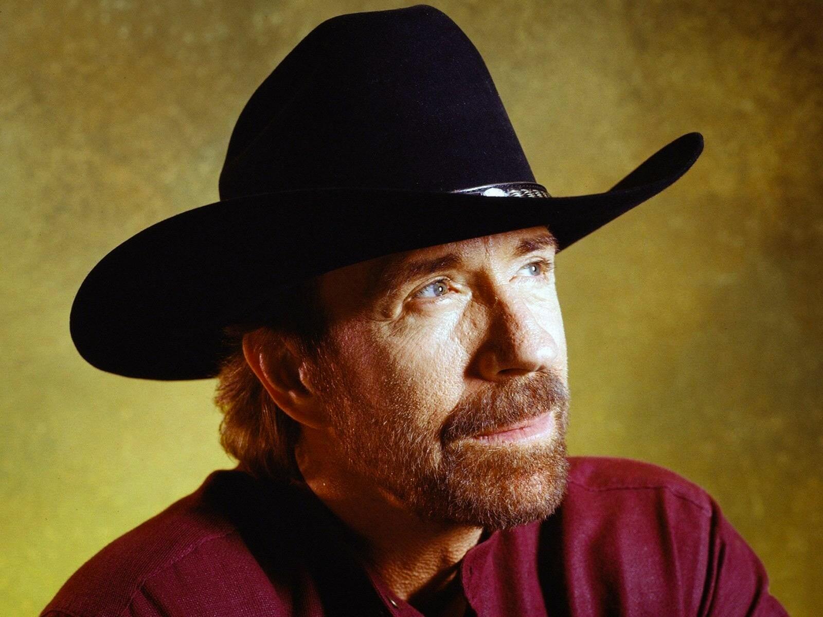 A legendary portrait of actor Chuck Norris in western attire, captured in a reflective and pensive pose.