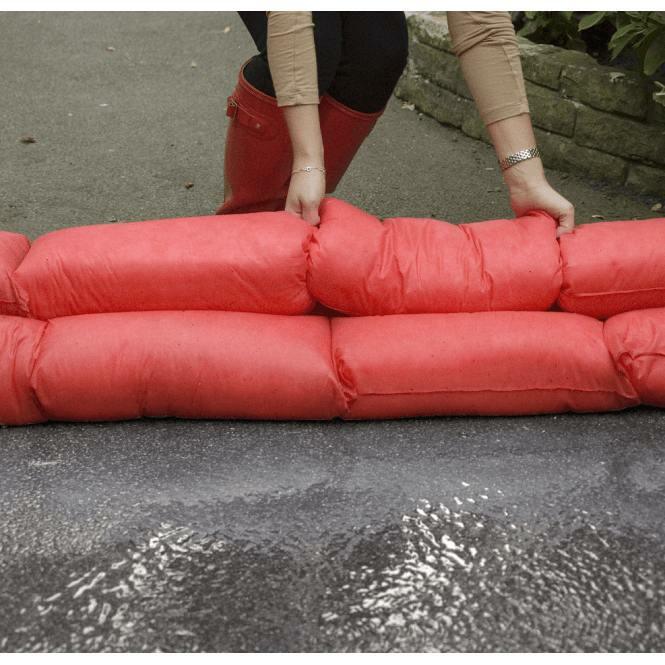 hydrosnake being used by a woman to form a flood barrier