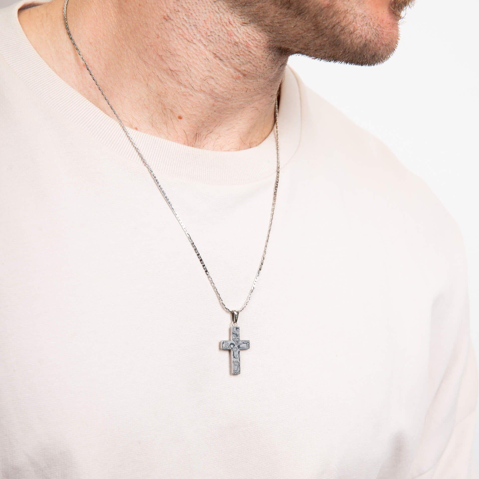 "fredbennett® Damascus Steel Cross Pendant with stainless steel chain – featuring rippling grain texture and bold structure. Hypoallergenic and presented in a suede pouch from Gold and Diamonds."