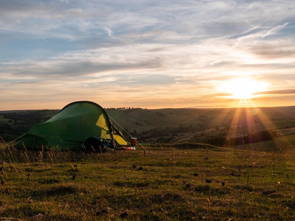 vango tent on top of hill with sunset in the background