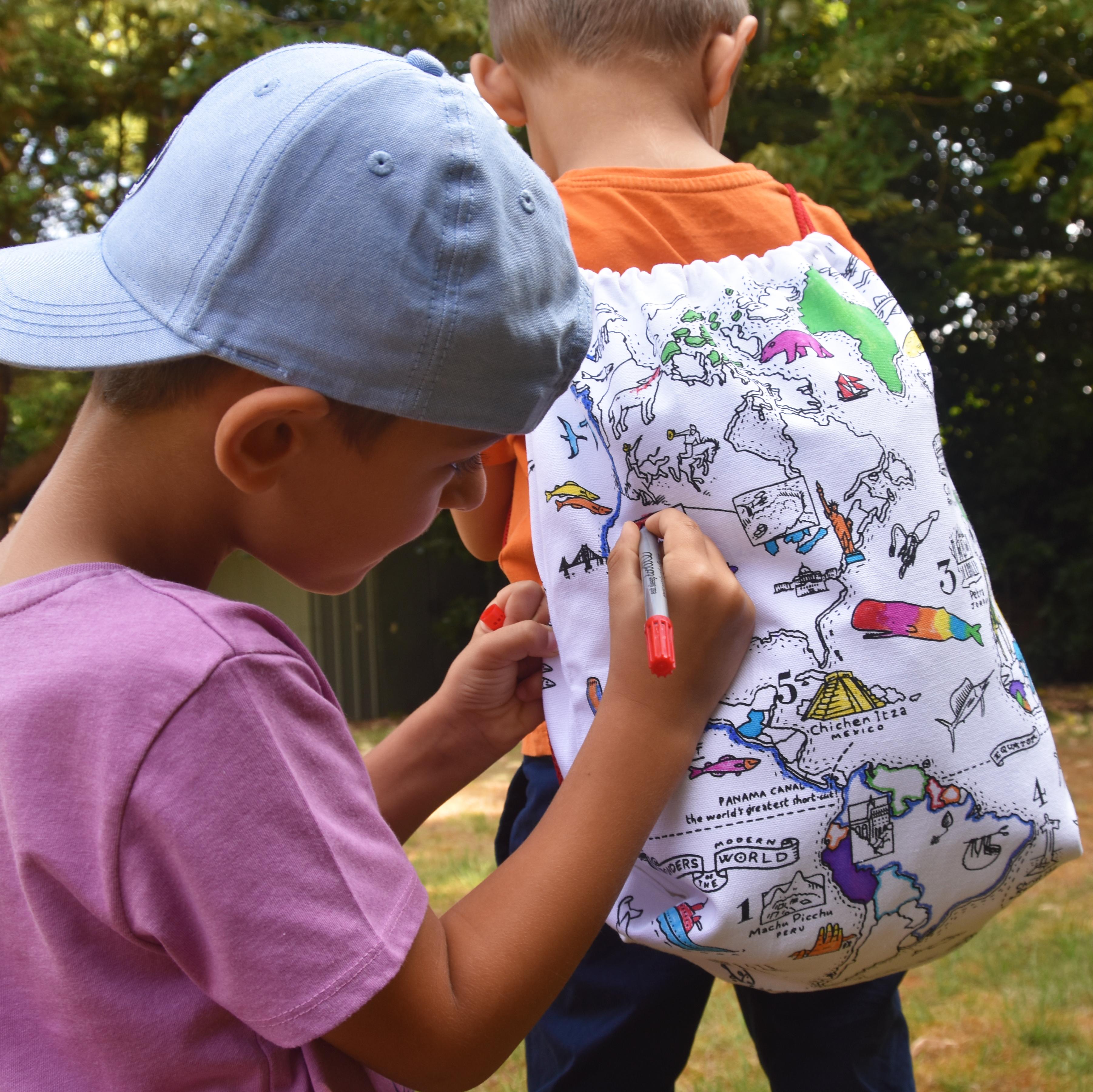 Children colouring in the world map bag while another is wearing it