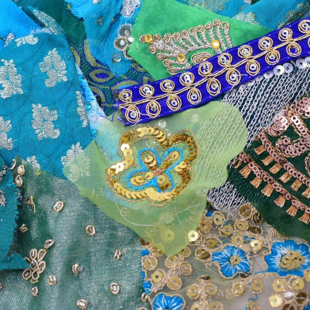 Close up detail of some embellished sari fabric scraps in a green and blue colour mix