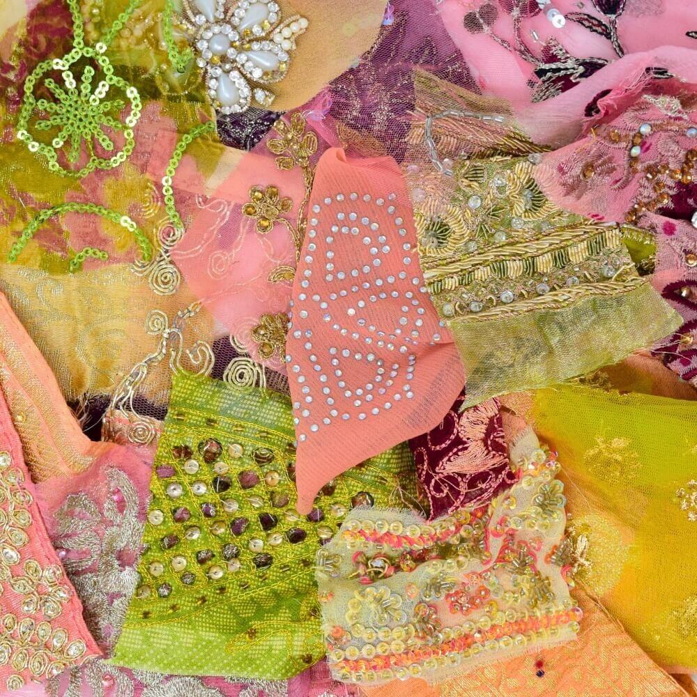 Flat lay of some very small pieces of embellished sari fabric scraps in a plum, pear and pinkt colour mix