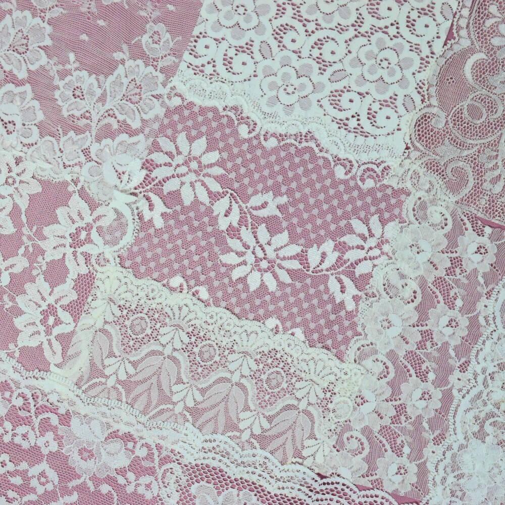 Diagonal flatlay of some pieces of white lace fabric and trims arranged on a lilac background