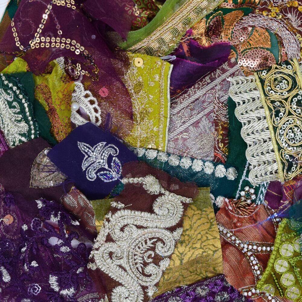 Flat lay of some very small, embellished sari fabric scraps in a green, purple and brown colour mix