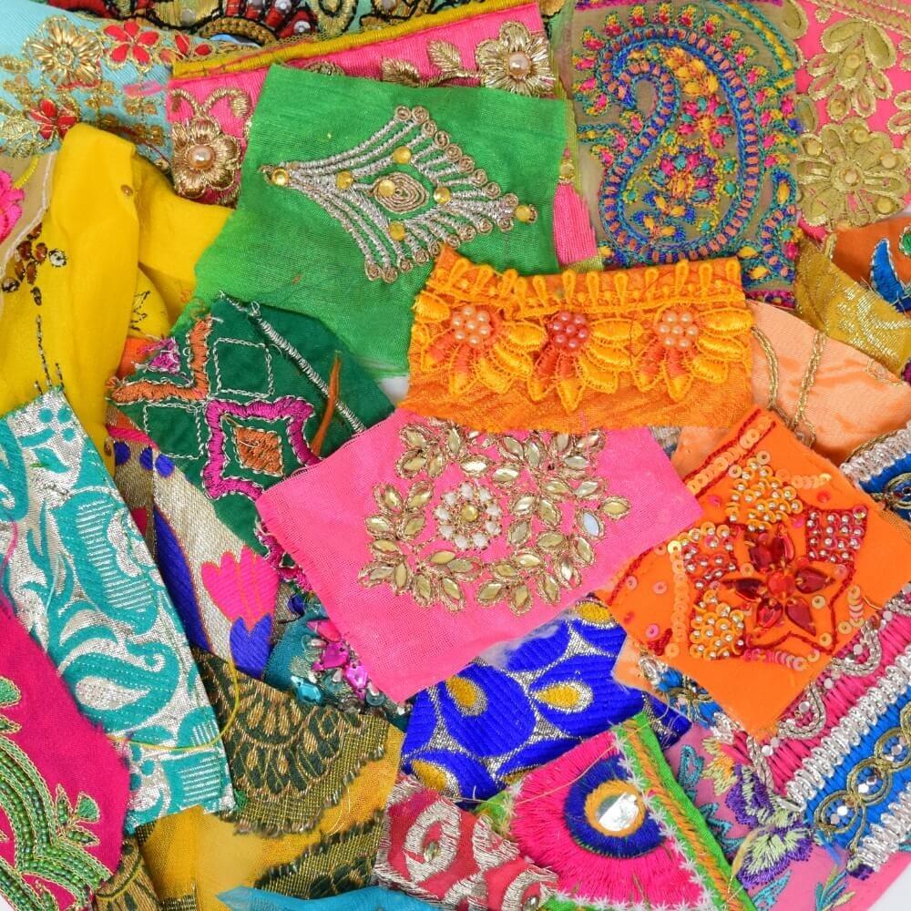 Flat lay of some very small pieces of embellished sari fabric scraps in a rainbow bright colour mix