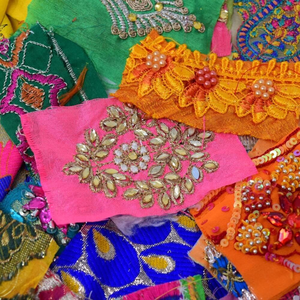 Close up detail of some embellished sari fabric scraps in a rainbow bright colour mix
