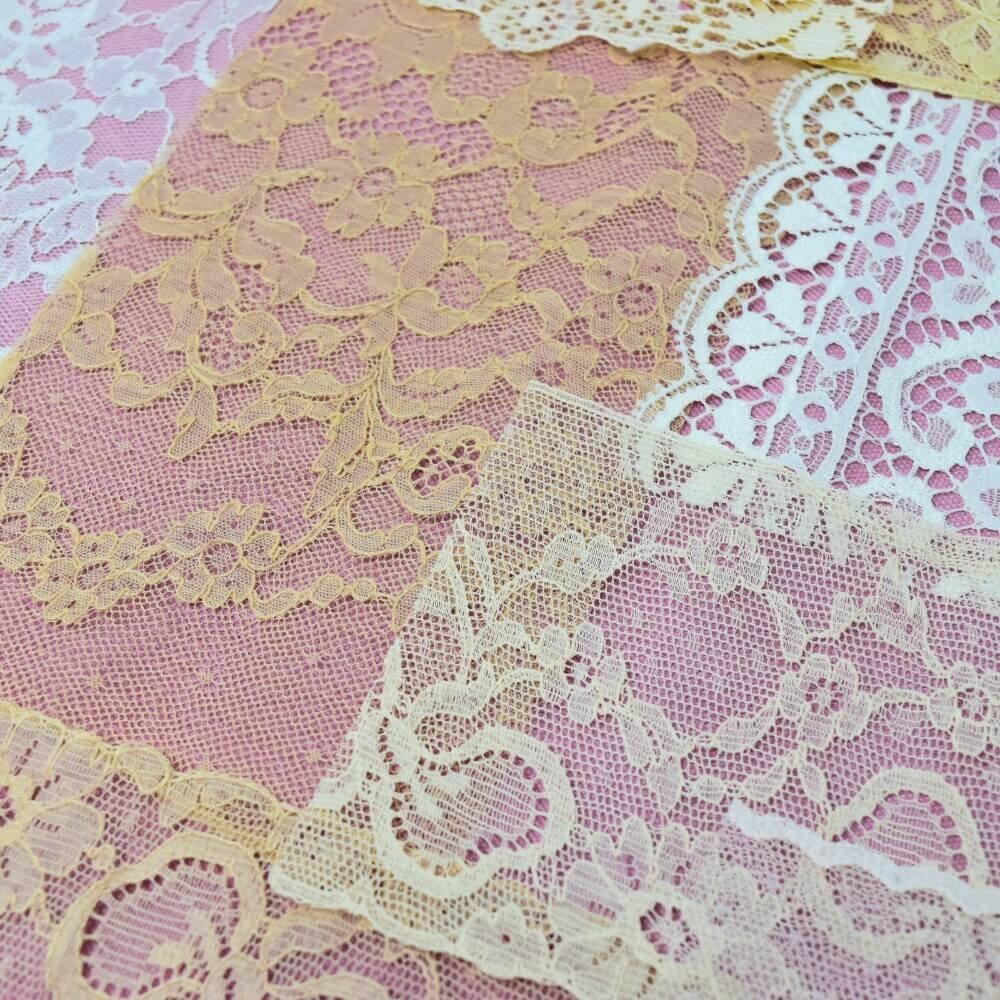 Close up of the detail and patterns on some pieces of off-white lace fabrics and trim