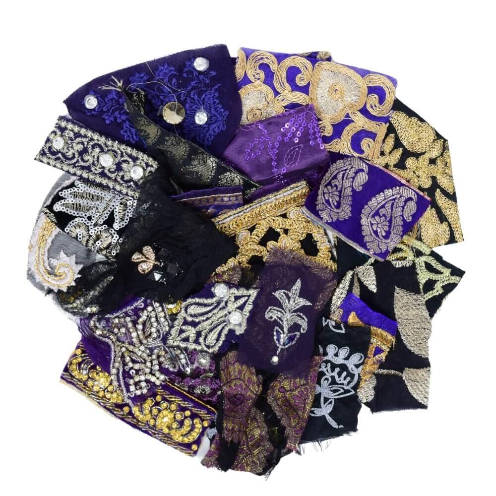 Flat lay of very small pieces of purple and black sari fabric scraps arranged in a rough circular shape on a white background