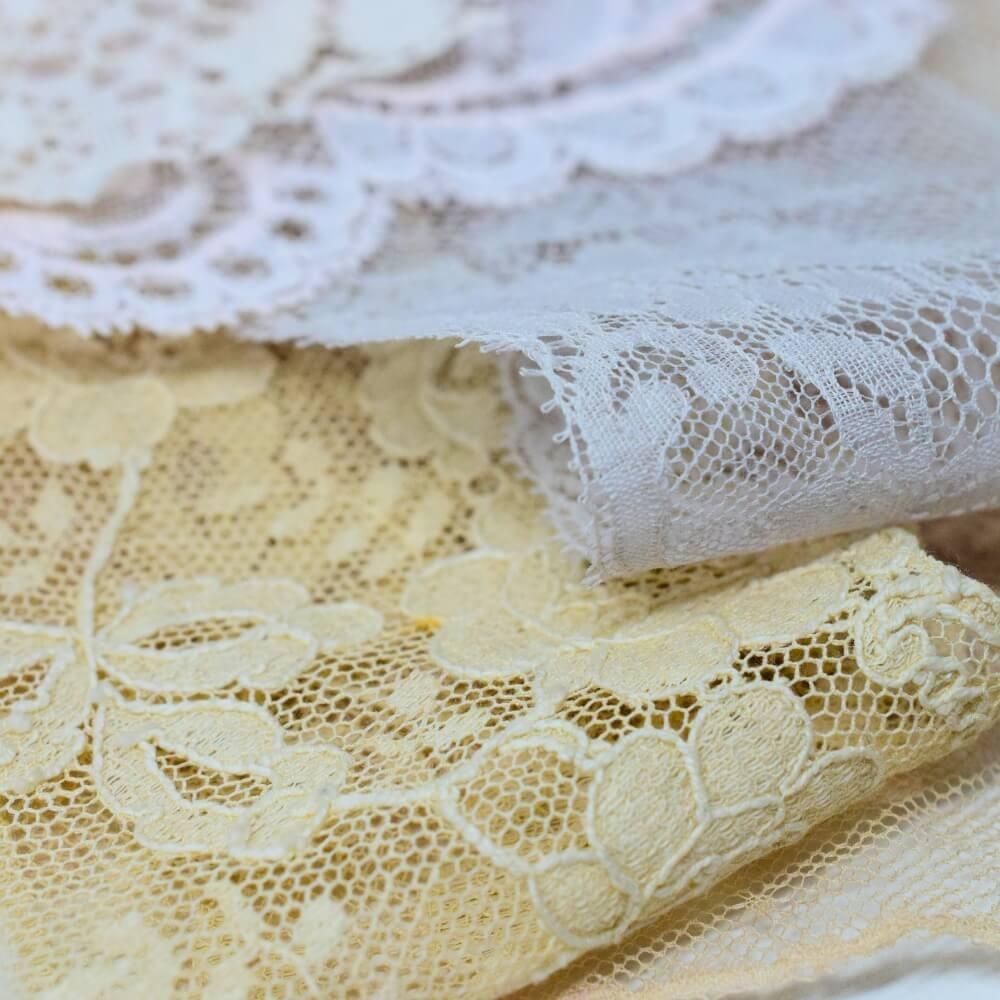 Macro detail of the patterns on some pieces of off- white lace fabrics and trim