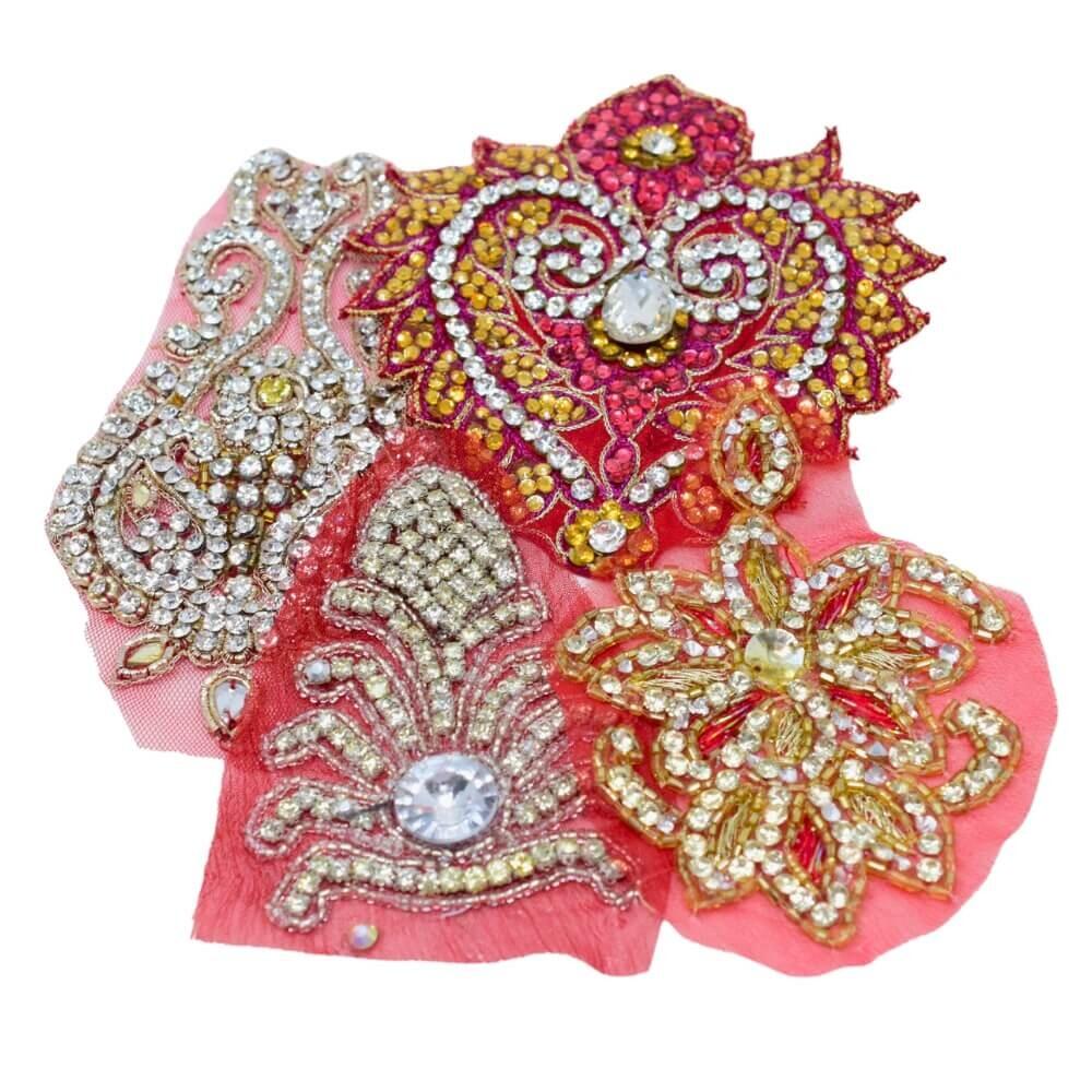 Flat lay of four red highly embellished and sparkly Indian motif fabric appliques on a white background