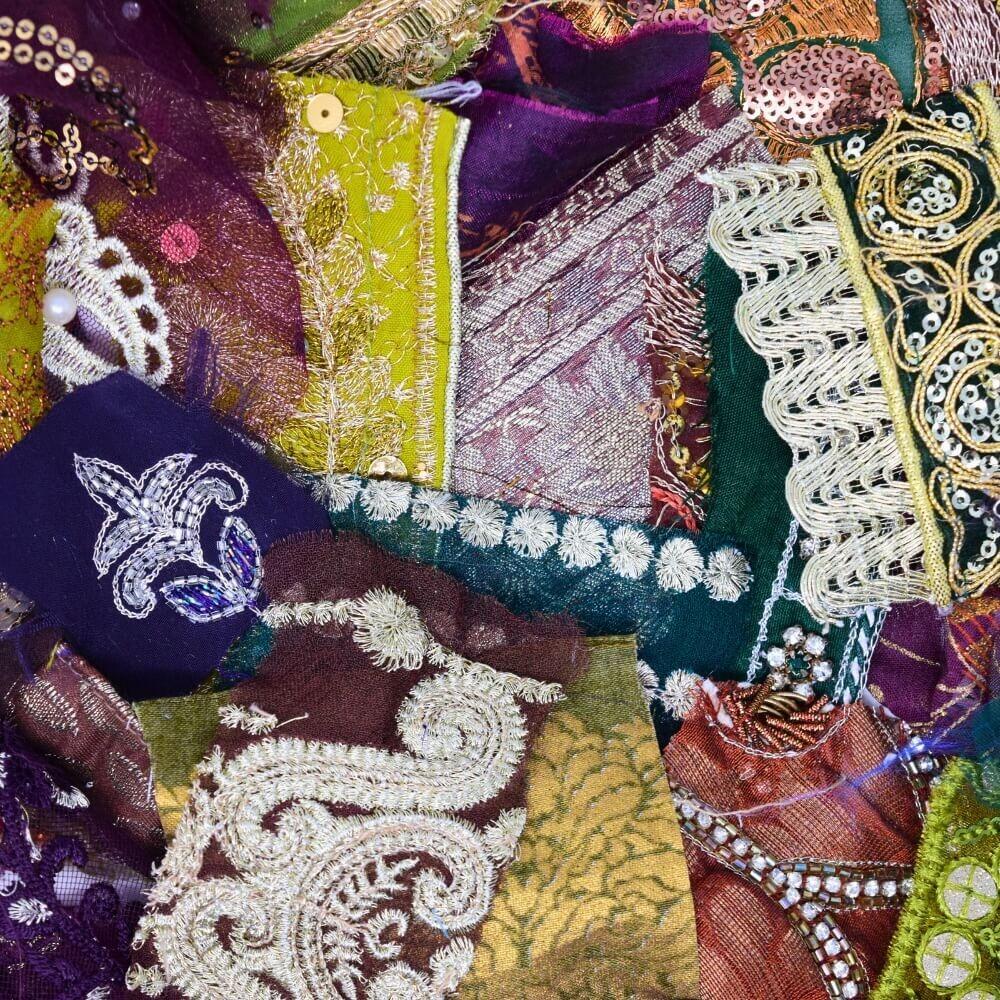 Close up detail of some very small, embellished sari fabric scraps in a green, purple and brown colour mix