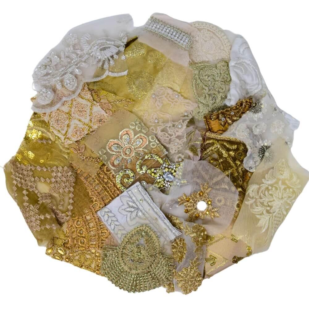 Flat lay of very small pieces of neutral coloured sari fabric scraps arranged in a rough circular shape on a white background