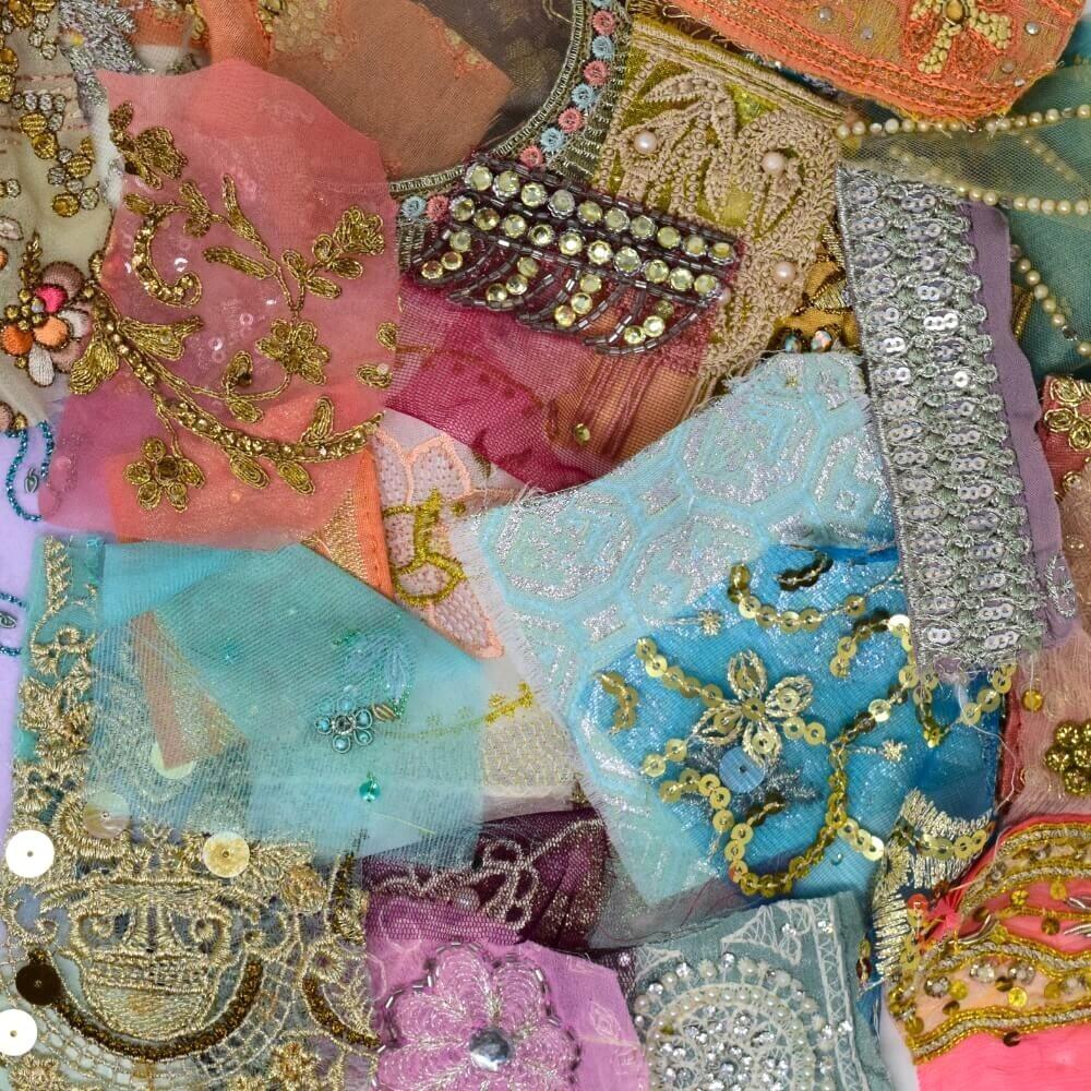 Flat lay of some very small pieces of embellished sari fabric scraps in a muted and pastel colour mix