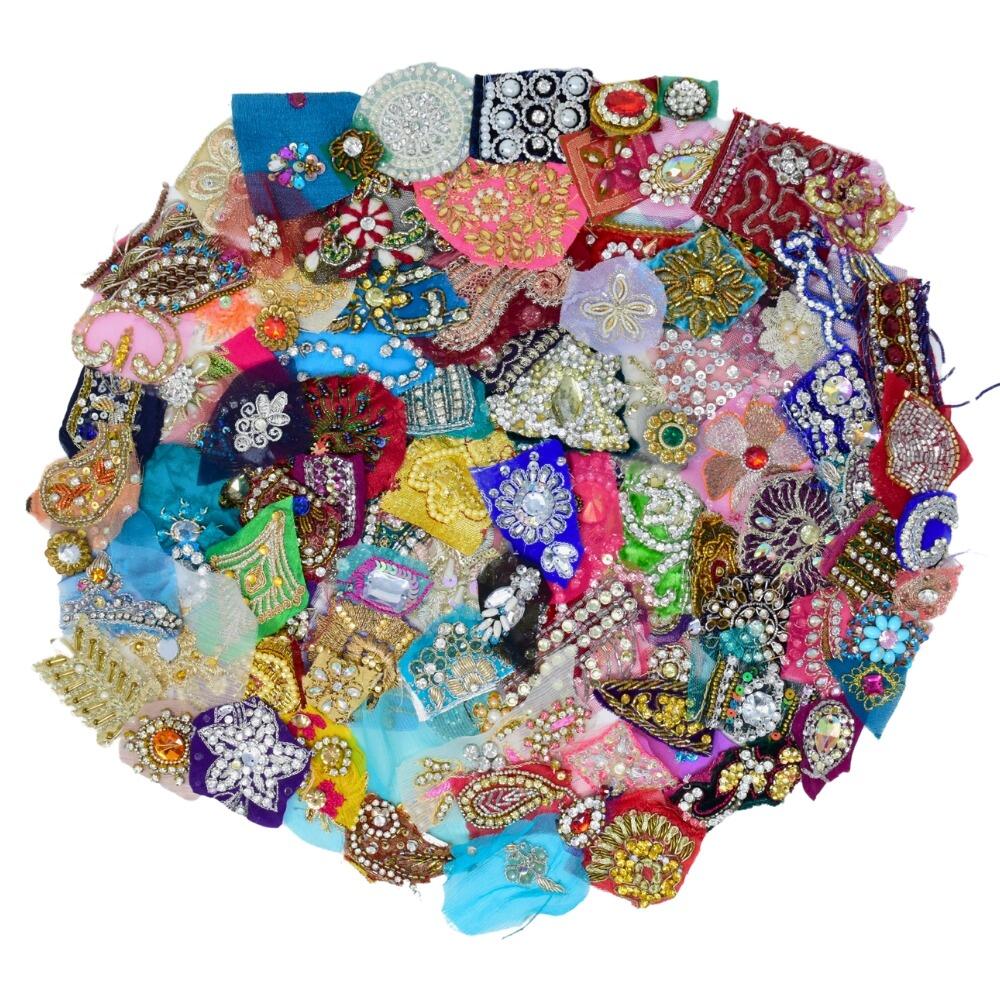 Flay lay of a large selection of sparkly sari fabric embellishment scraps arranged in a circular shape on a white background
