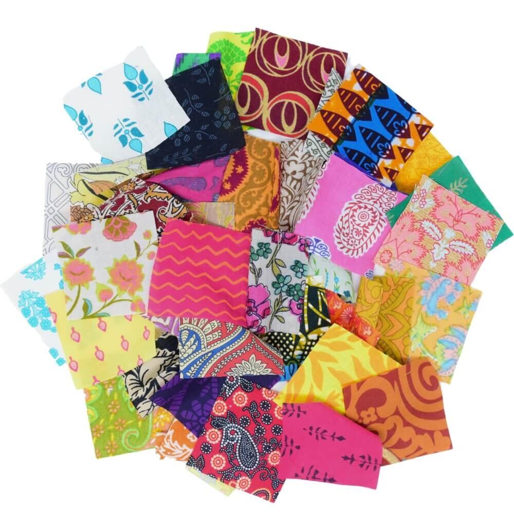 Flat lay of a selection of colourful ethnic print fabric squares arranged in a rough circular shape on a white background
