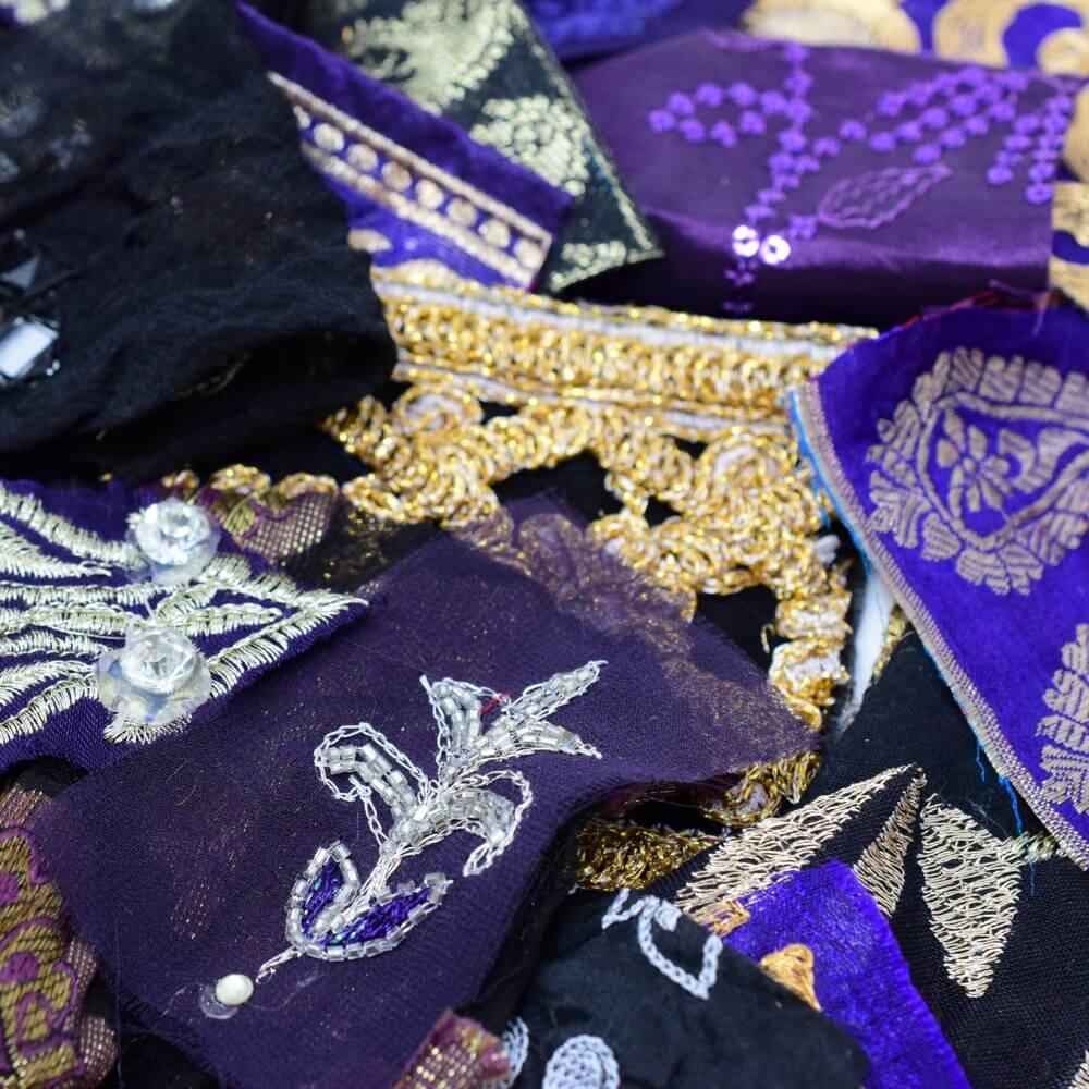 Close up detail of some very small pieces of embellished sari fabric scraps in a purple and black colour mix