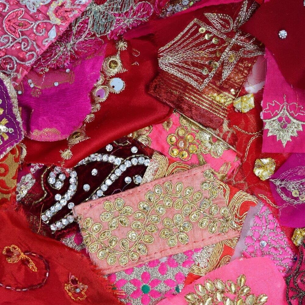 Close up detail of some embellished sari fabric scraps in a pink and red colour mix