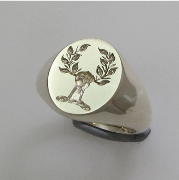 Hand holding wreath crest engraved silver signet ring