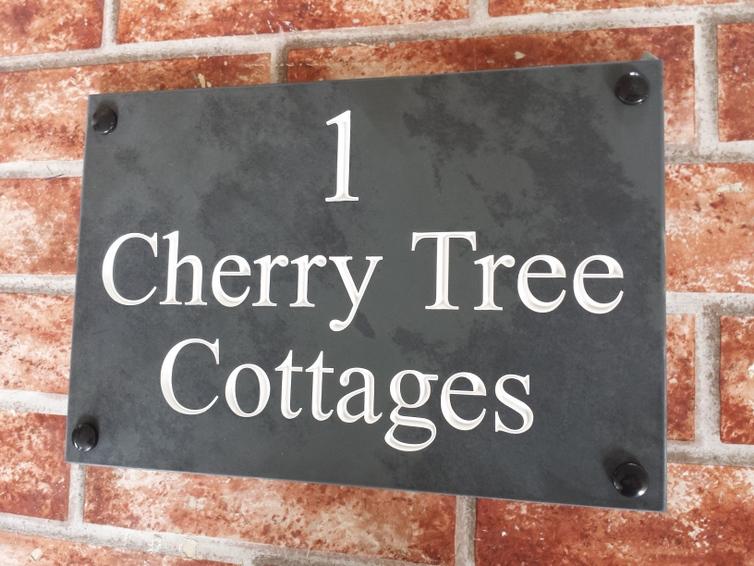 Slate house sign depicting 1 Cherry Tree Cottage with a white inlay