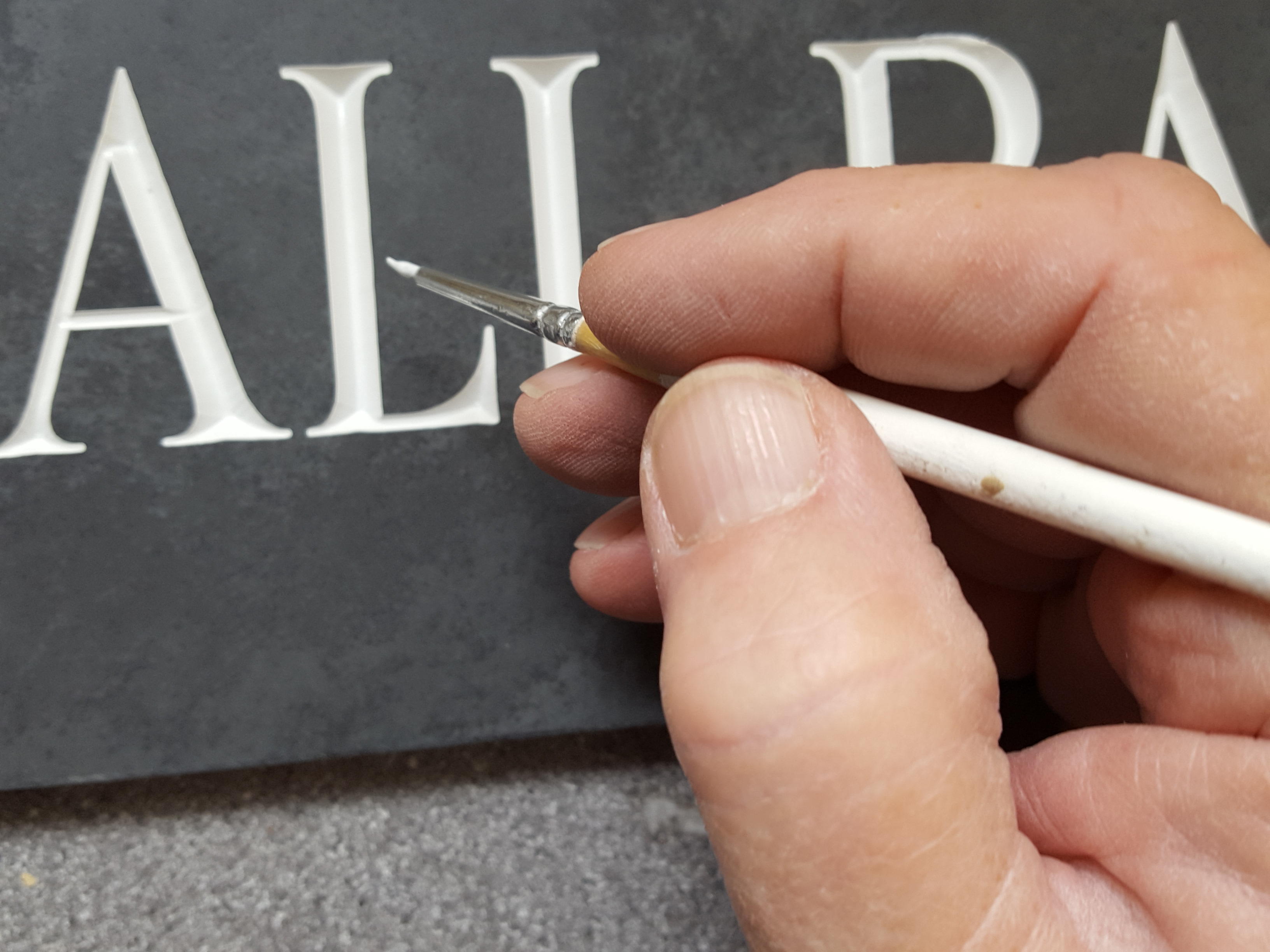 White paint touch up on engraved v-groove letters in slate