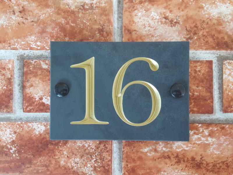 Slate house sign depicting number 16 with a gold inlay