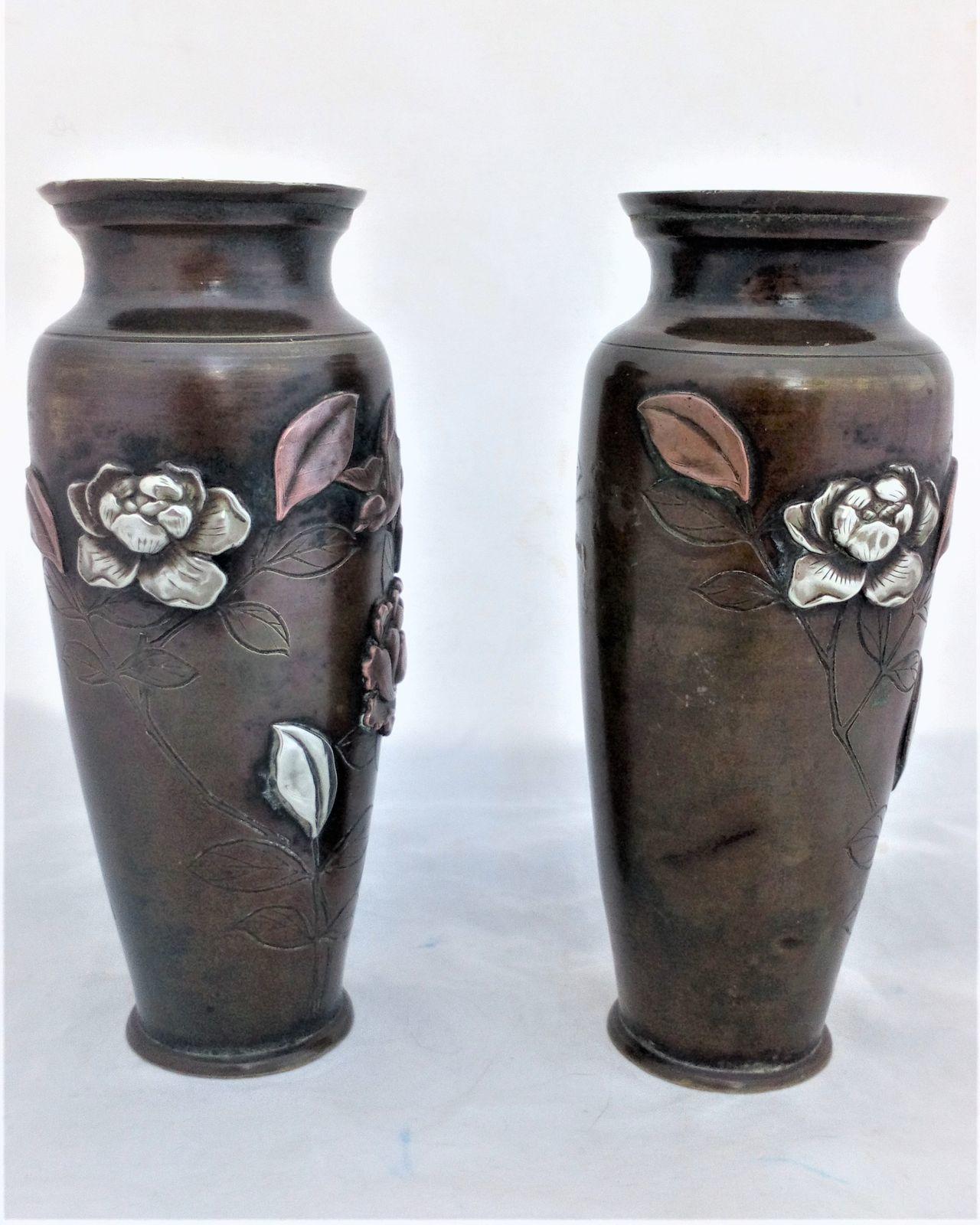 A pair of antique Japanese patinated bronze vases decorated with applied mixed metal birds and peony flowers made in the Meiji period circa 1900.  each 6 inches high and 2.5 inches diameter.