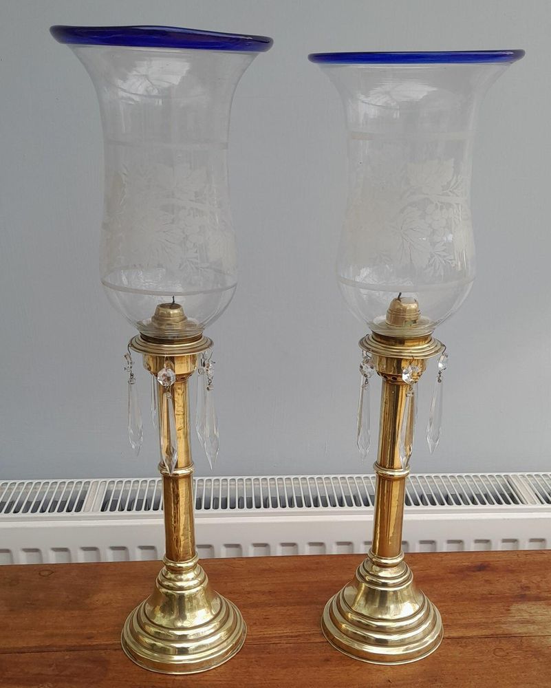 Pair of antique brass spring loaded hurricane candlesticks with grapevine etched glass shades with blue rim & cut glass prism lustre droppers 53 cm High 3.8 kg